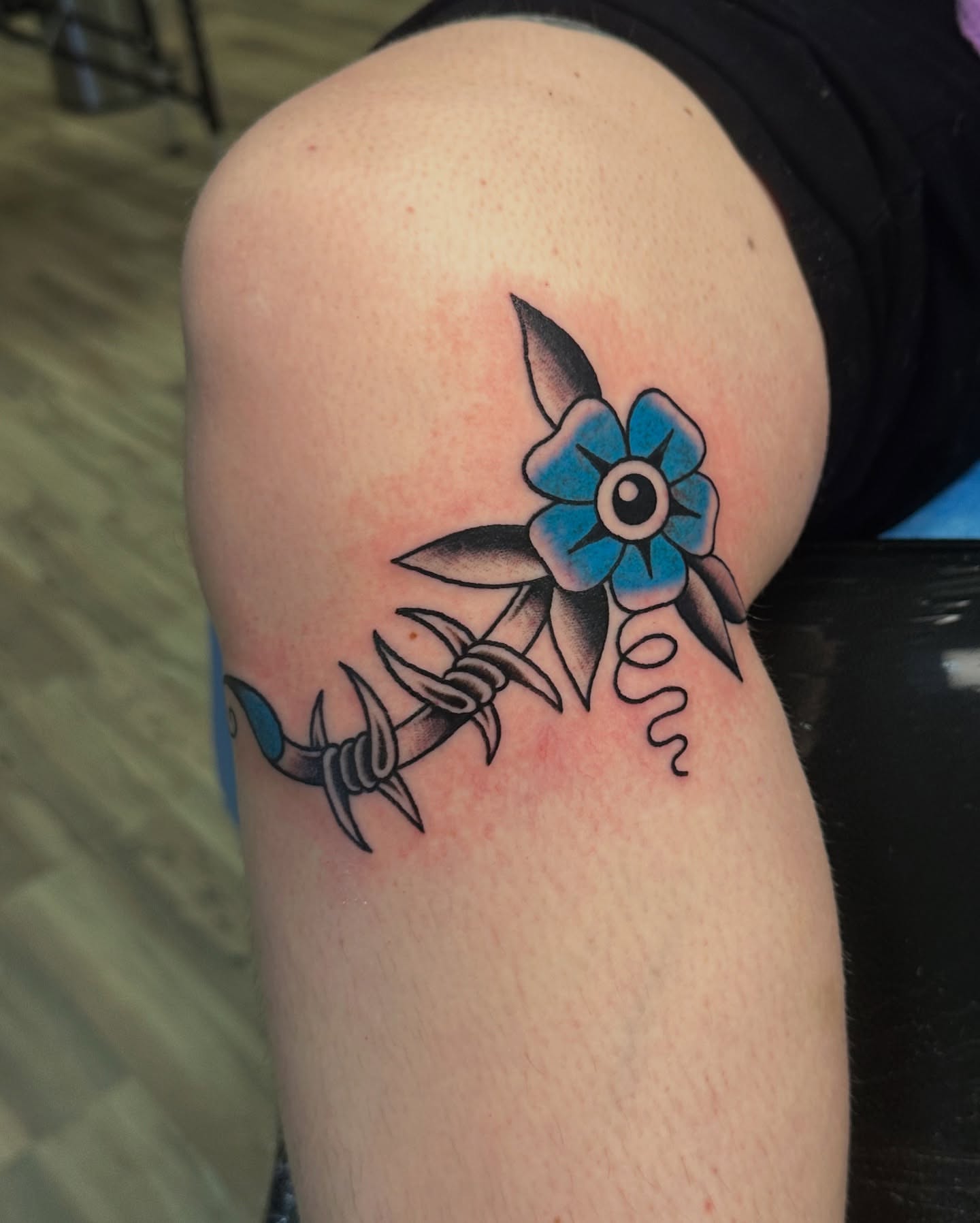 Barbed wire and flower American traditional tattoo on the thigh by Emily Masa