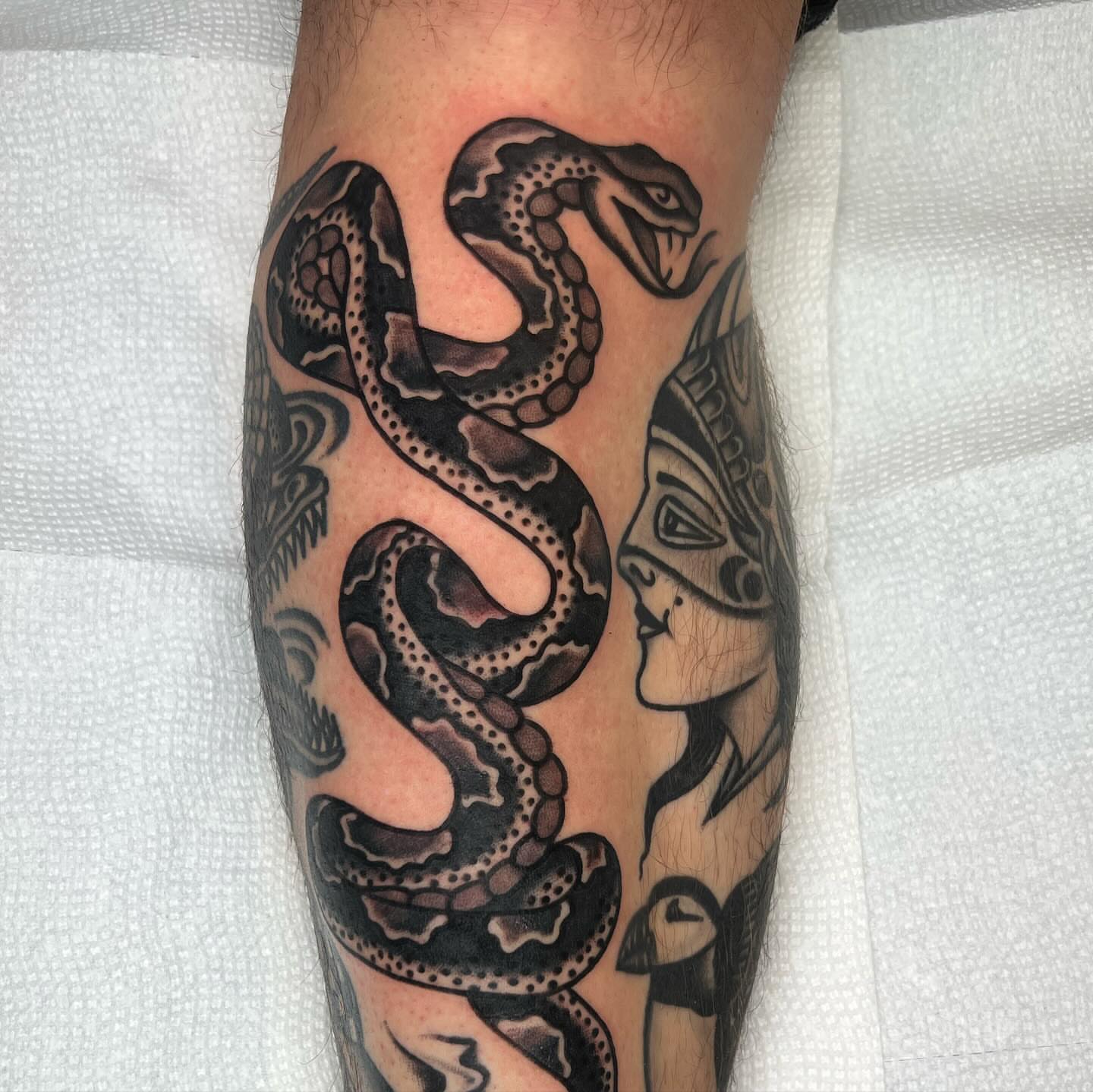 Snake and mask geometric tattoo on the forearm by Kevin Caruso