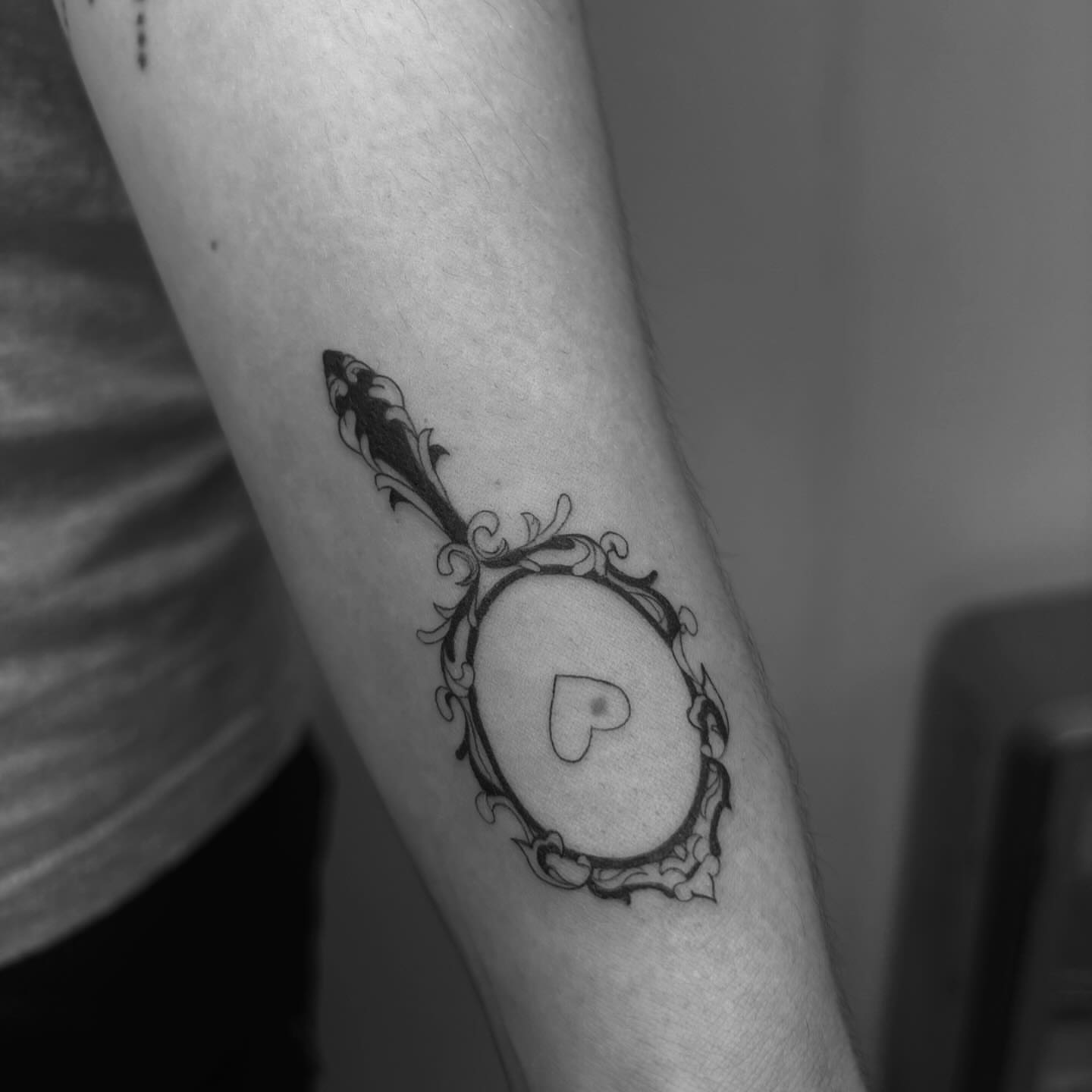 Mirror with heart black and grey tattoo on the forearm by Mady