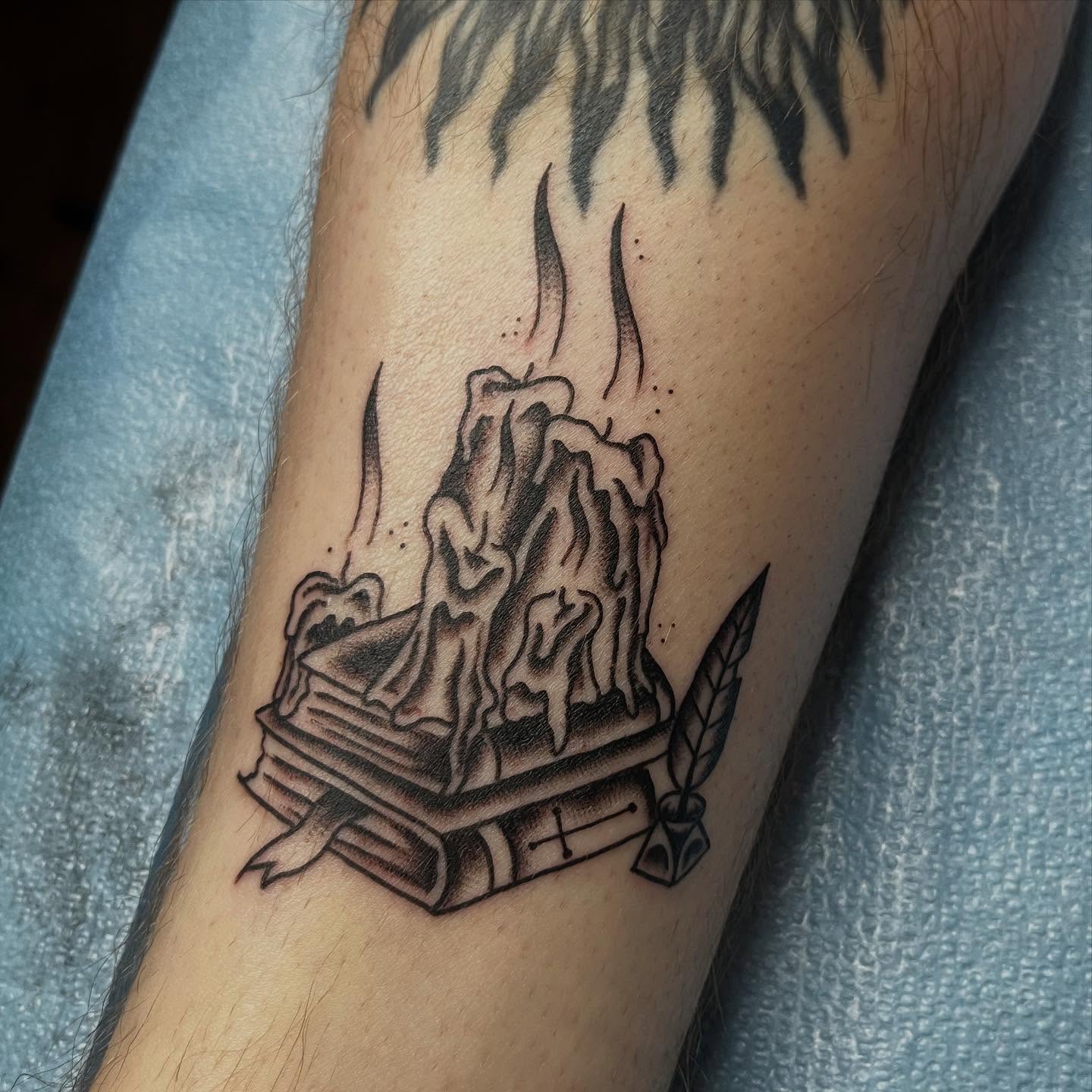 Burning book black and grey tattoo on the forearm by Mariah Nguyen