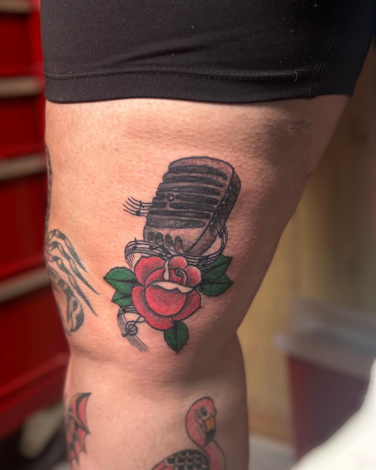 Microphone and rose American traditional tattoo on the thigh by Lee