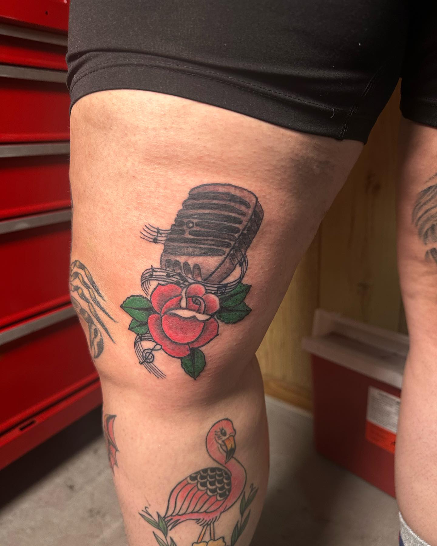 Microphone and rose American traditional tattoo on the thigh by Lee