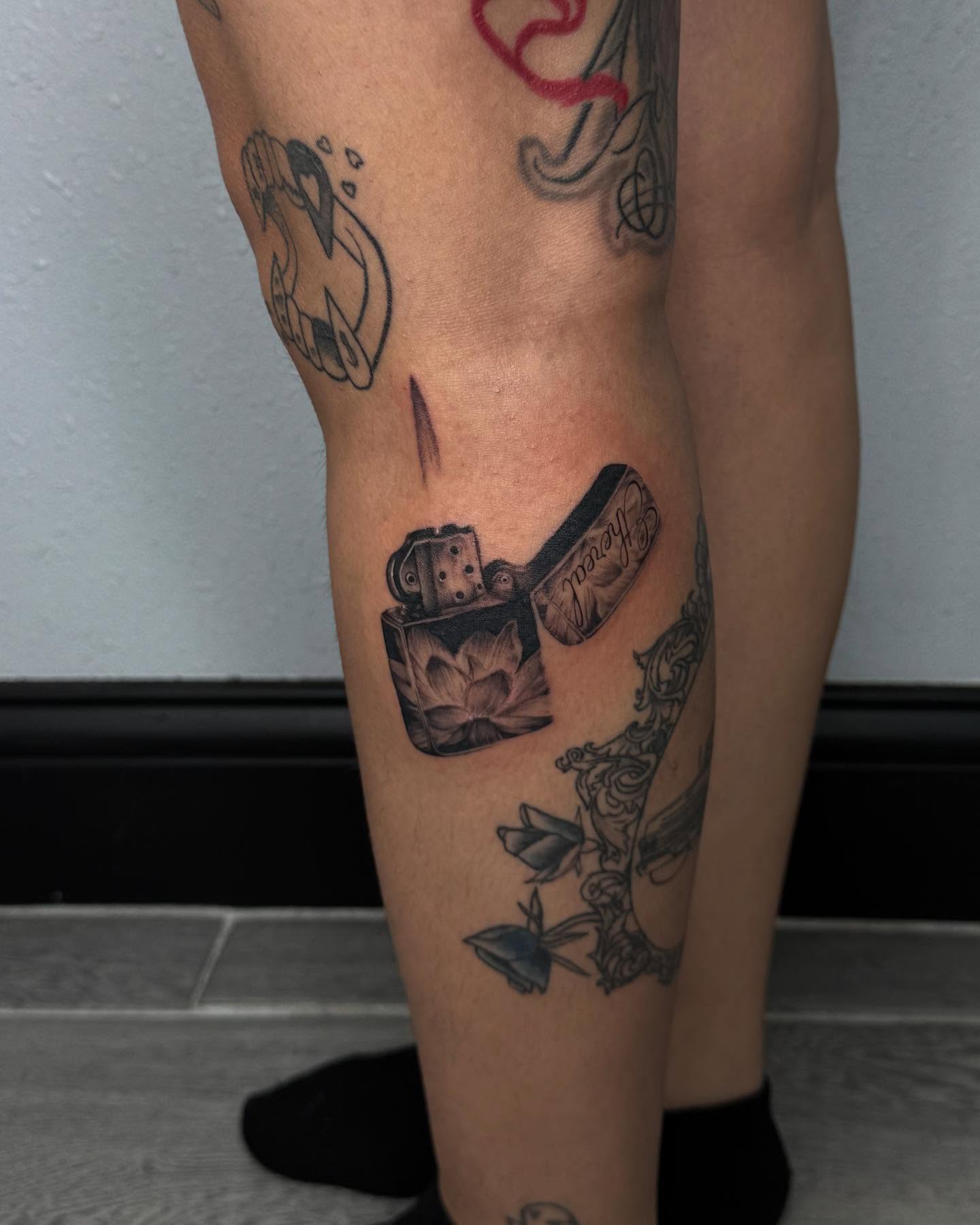 Lighter and lotus black and grey tattoo on the leg by Alexa Camacho
