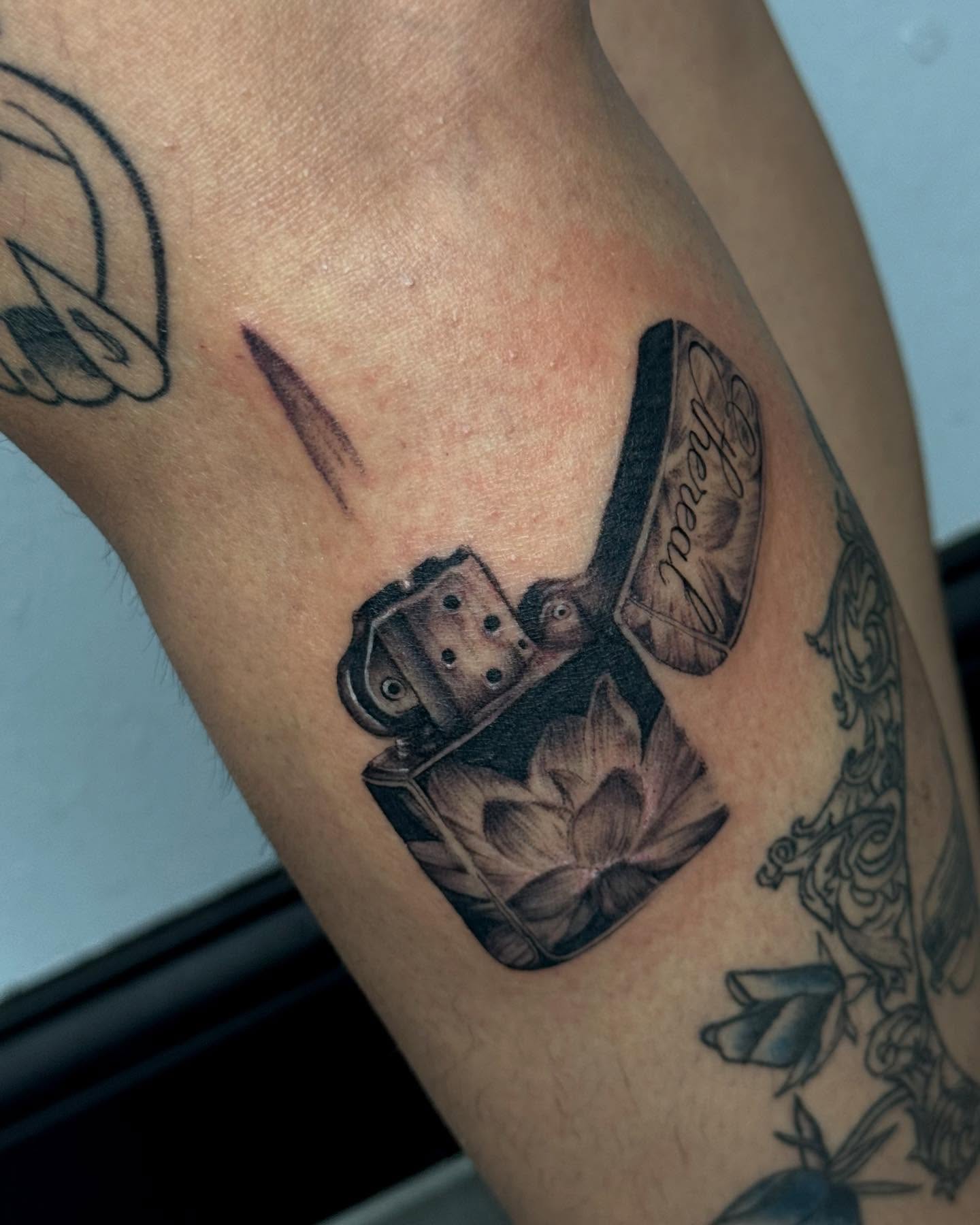 Lotus flower and lighter realism tattoo on the forearm by Alexa Camacho