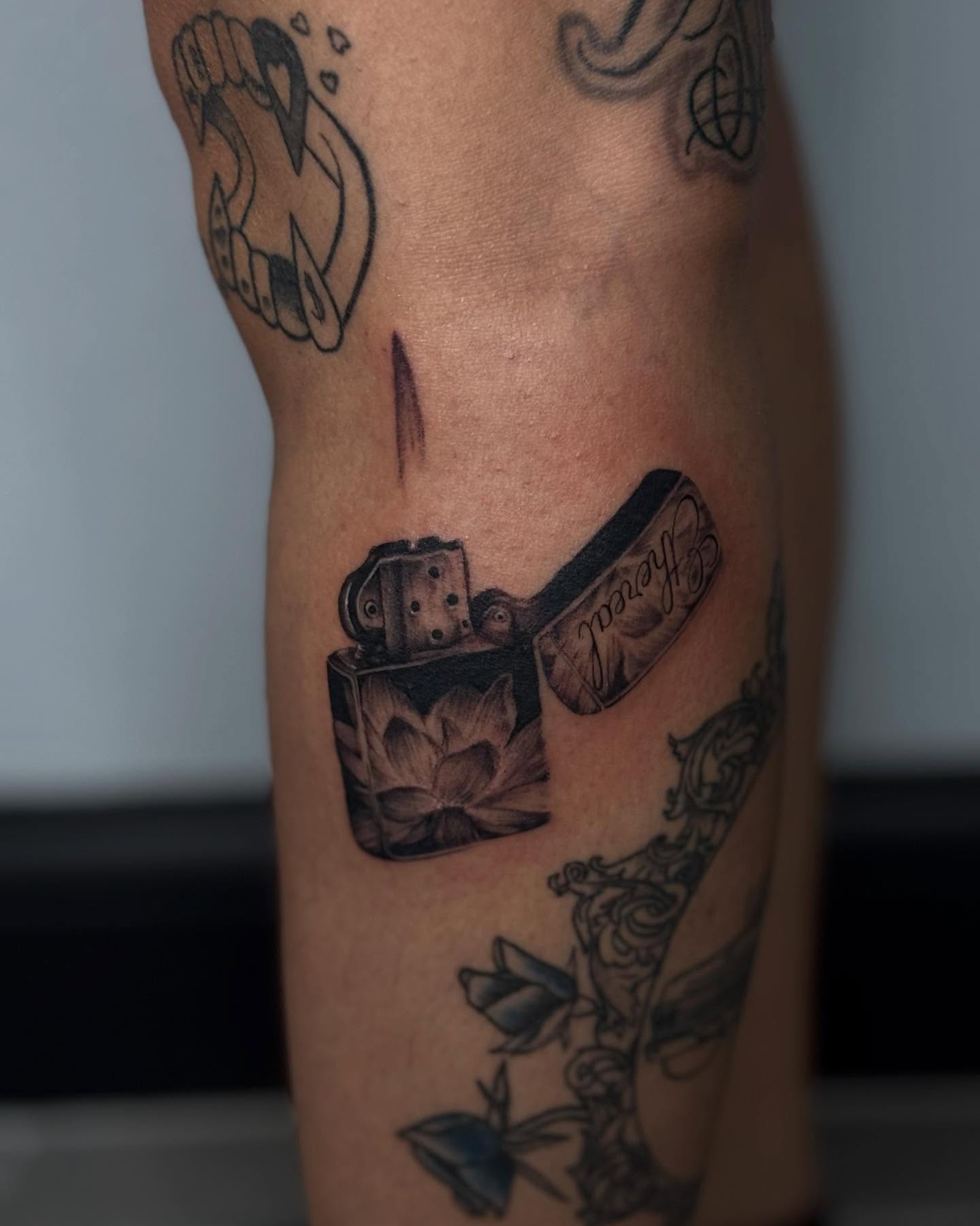 Lighter and lotus black and grey tattoo on the forearm by Alexa Camacho