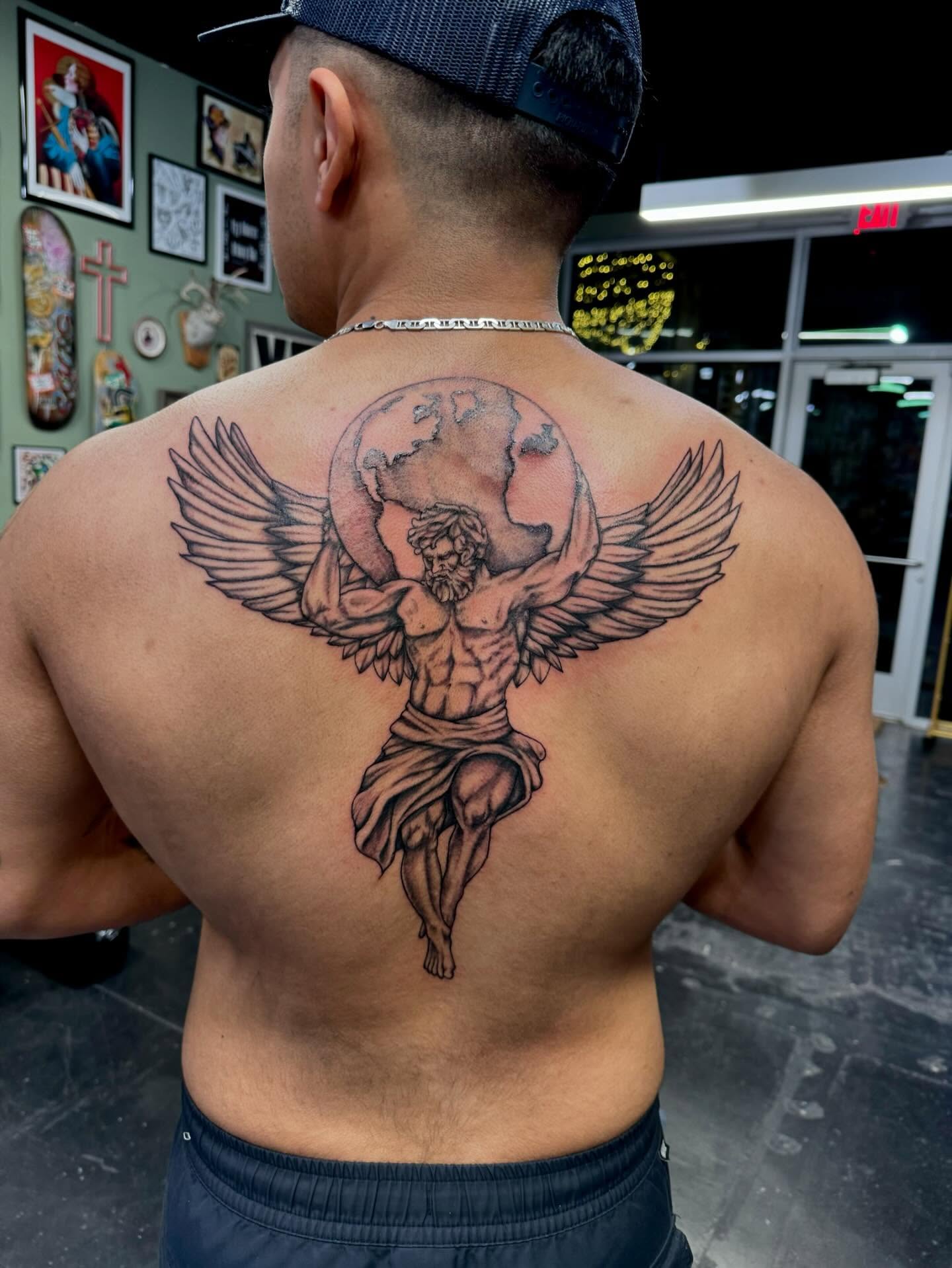 Winged angel holding globe black and grey tattoo on the back by Kenzie🖤