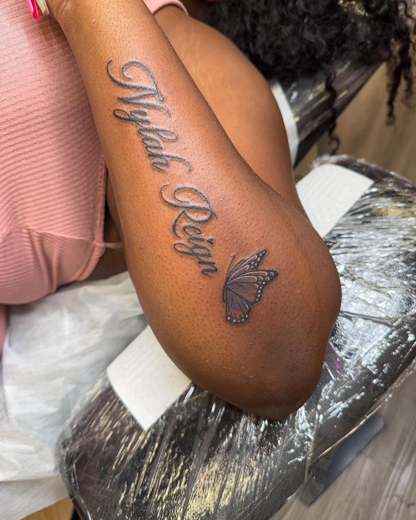 Name and butterfly lettering script tattoo on the thigh by Sierra 🩷
