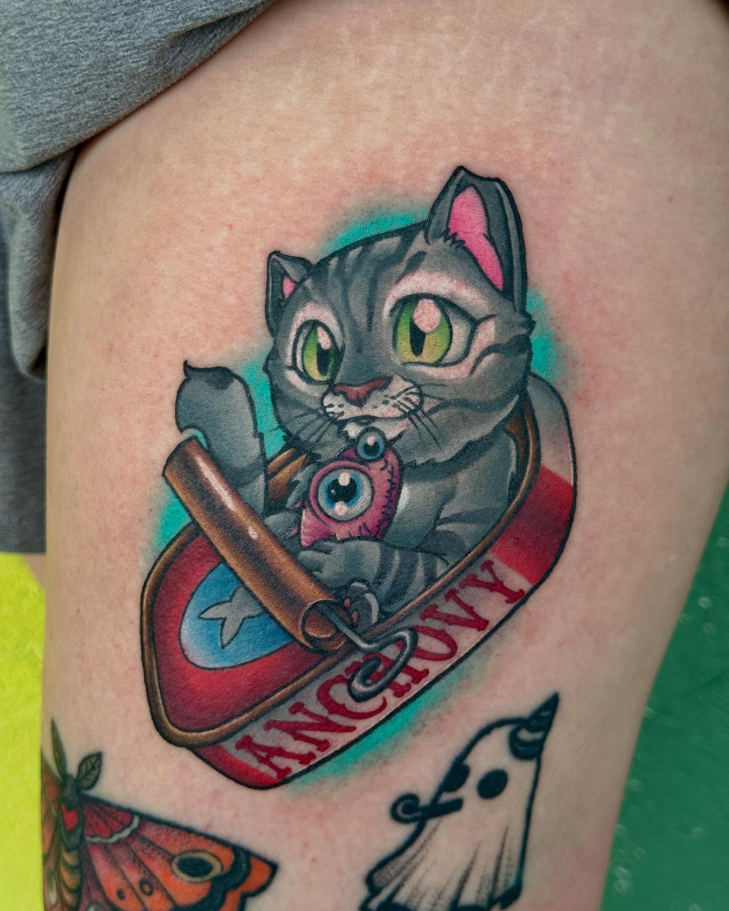 Cat holding fish American traditional tattoo on the thigh by Holle Hellfire