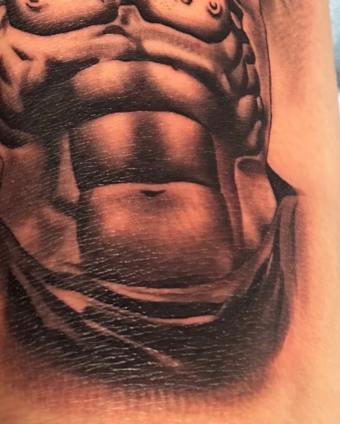 Muscular torso realism tattoo on the upper arm by Emma Sferdian🇷🇴