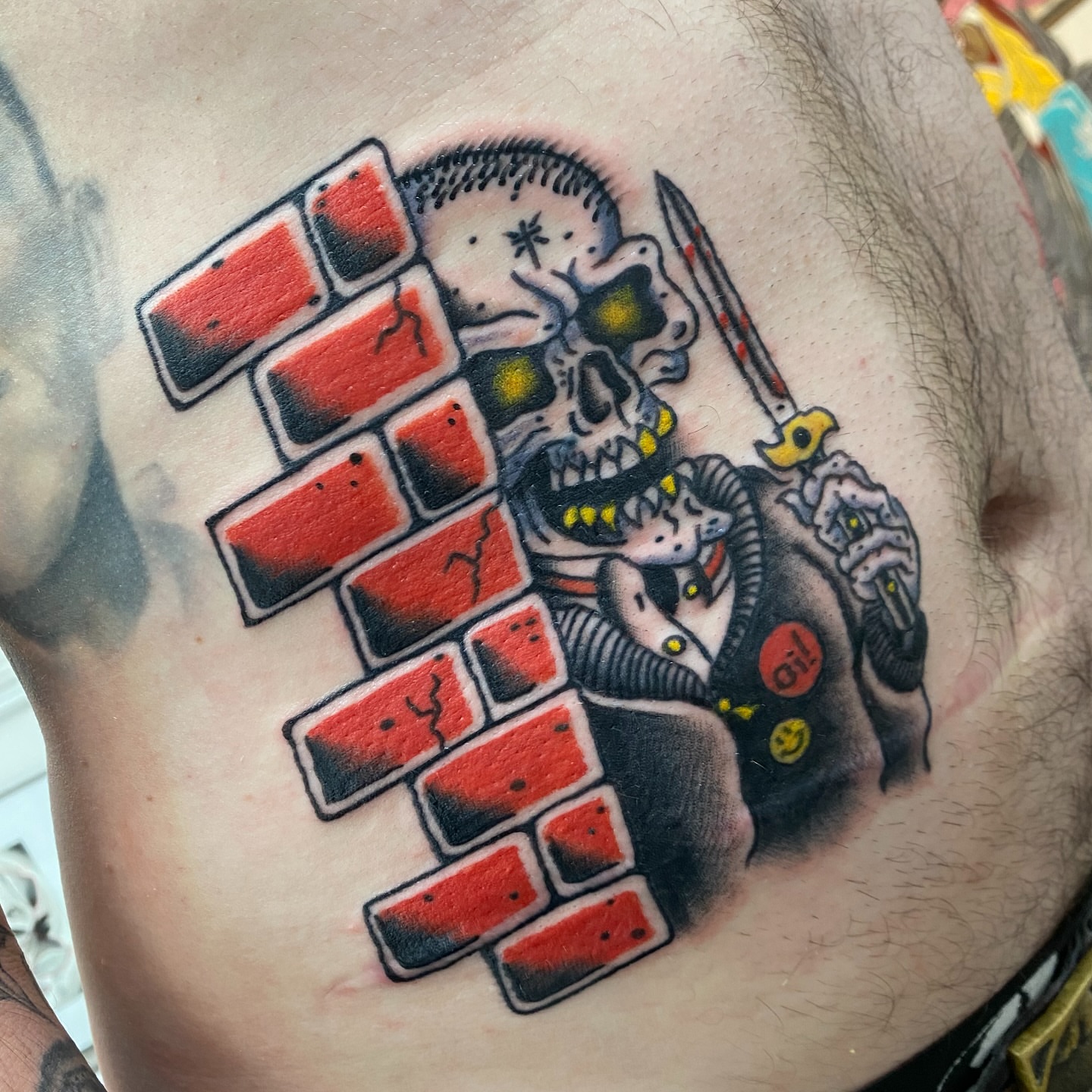 Skull with brick wall American traditional tattoo on the chest by Mike Tapia