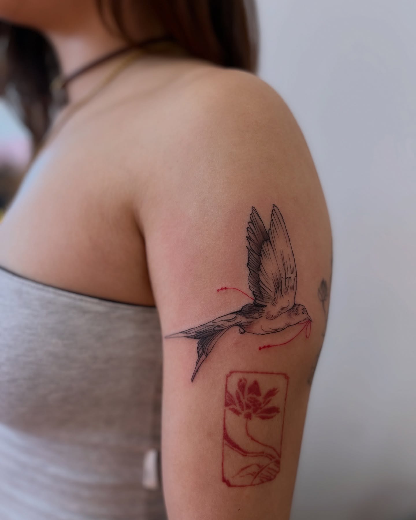 Bird and lotus realism tattoo on the upper arm by Ying Xeon