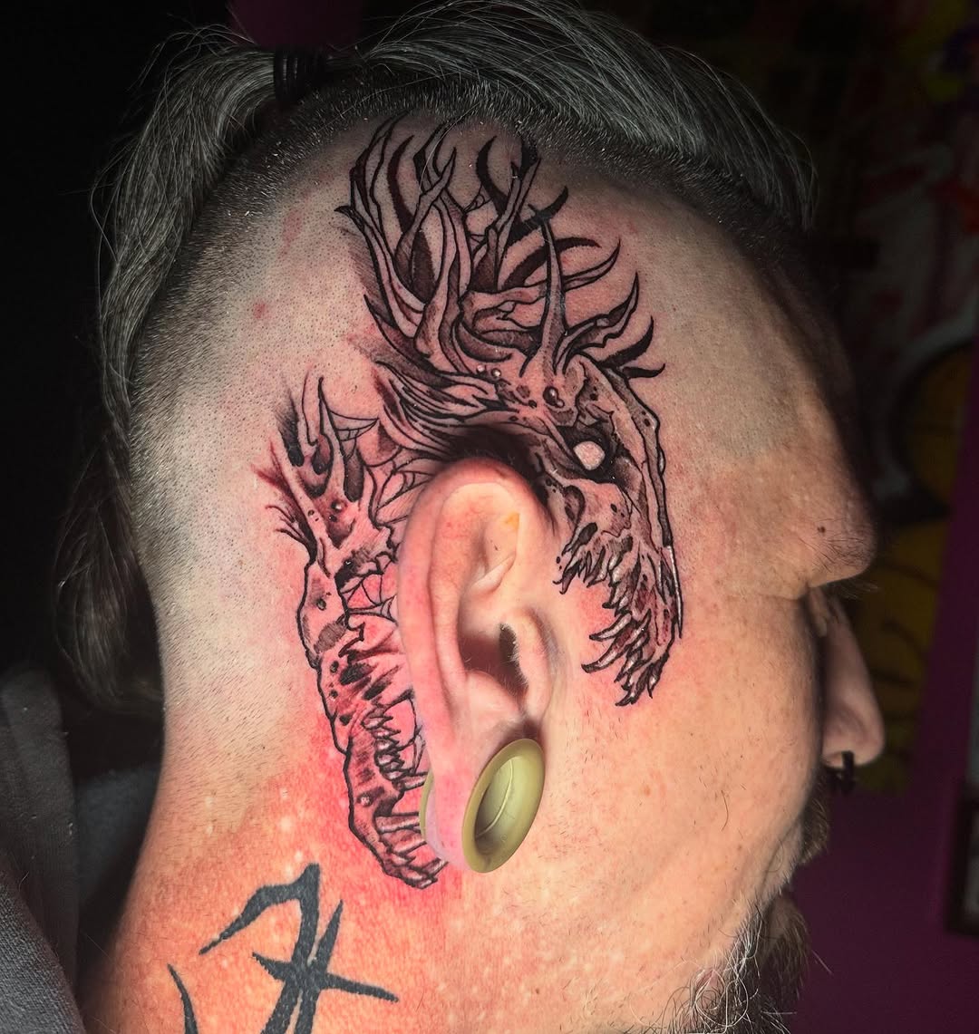 Demonic creature head dark art tattoo on the head by Skunk Punk