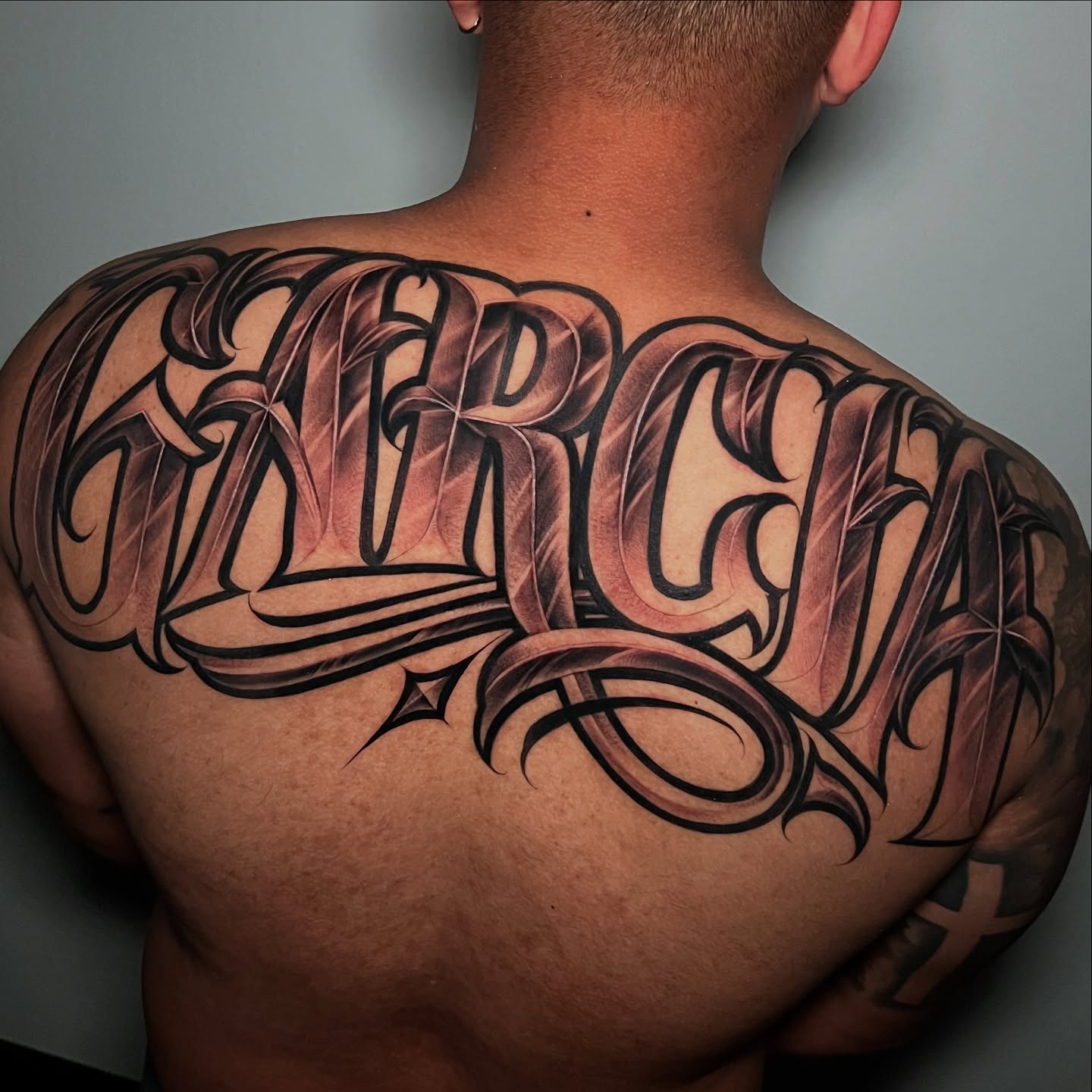 Garcia lettering script tattoo on the back by Flames, Cerritos, California