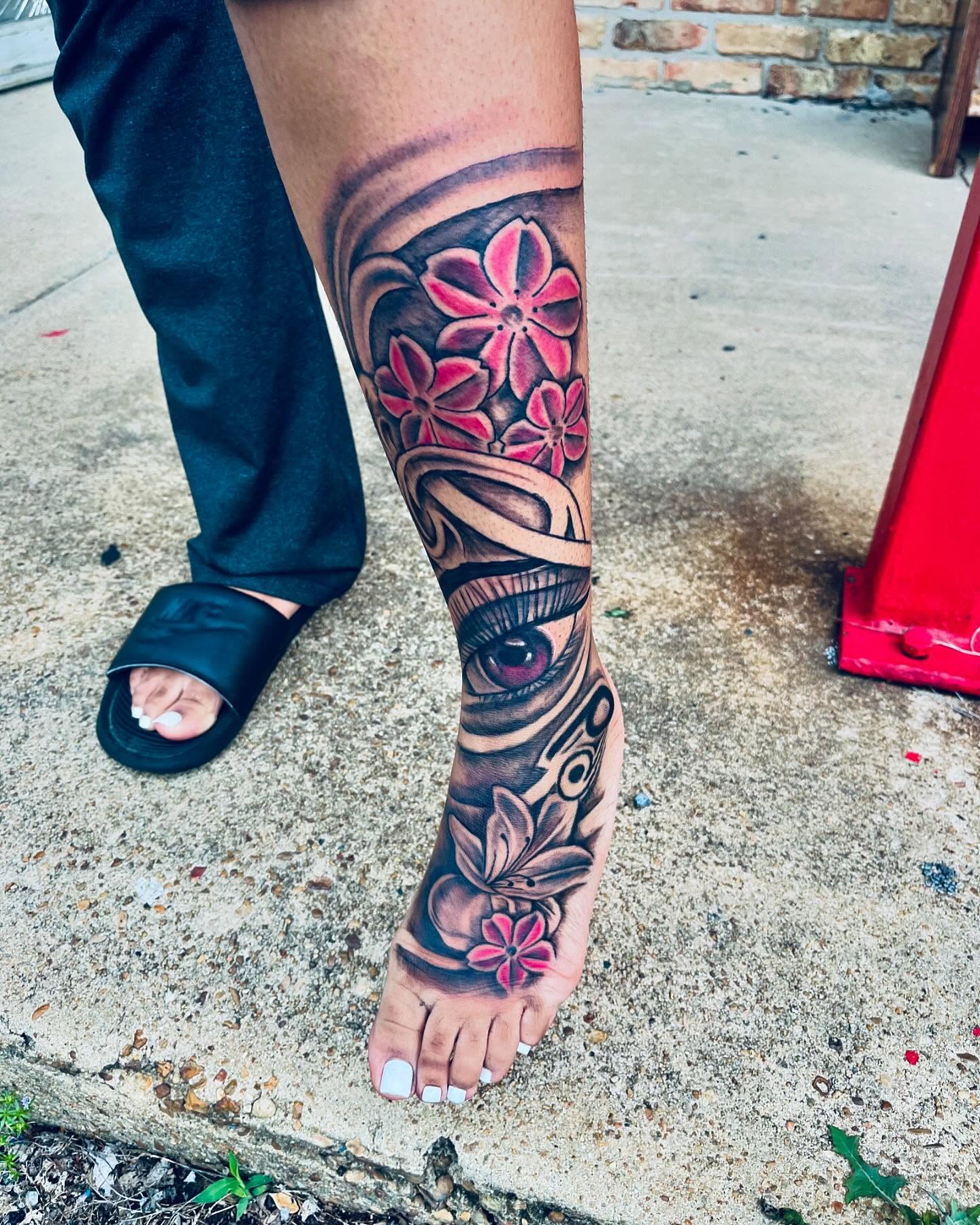 Eye and flowers realism tattoo on the calf by GrindHard Quen