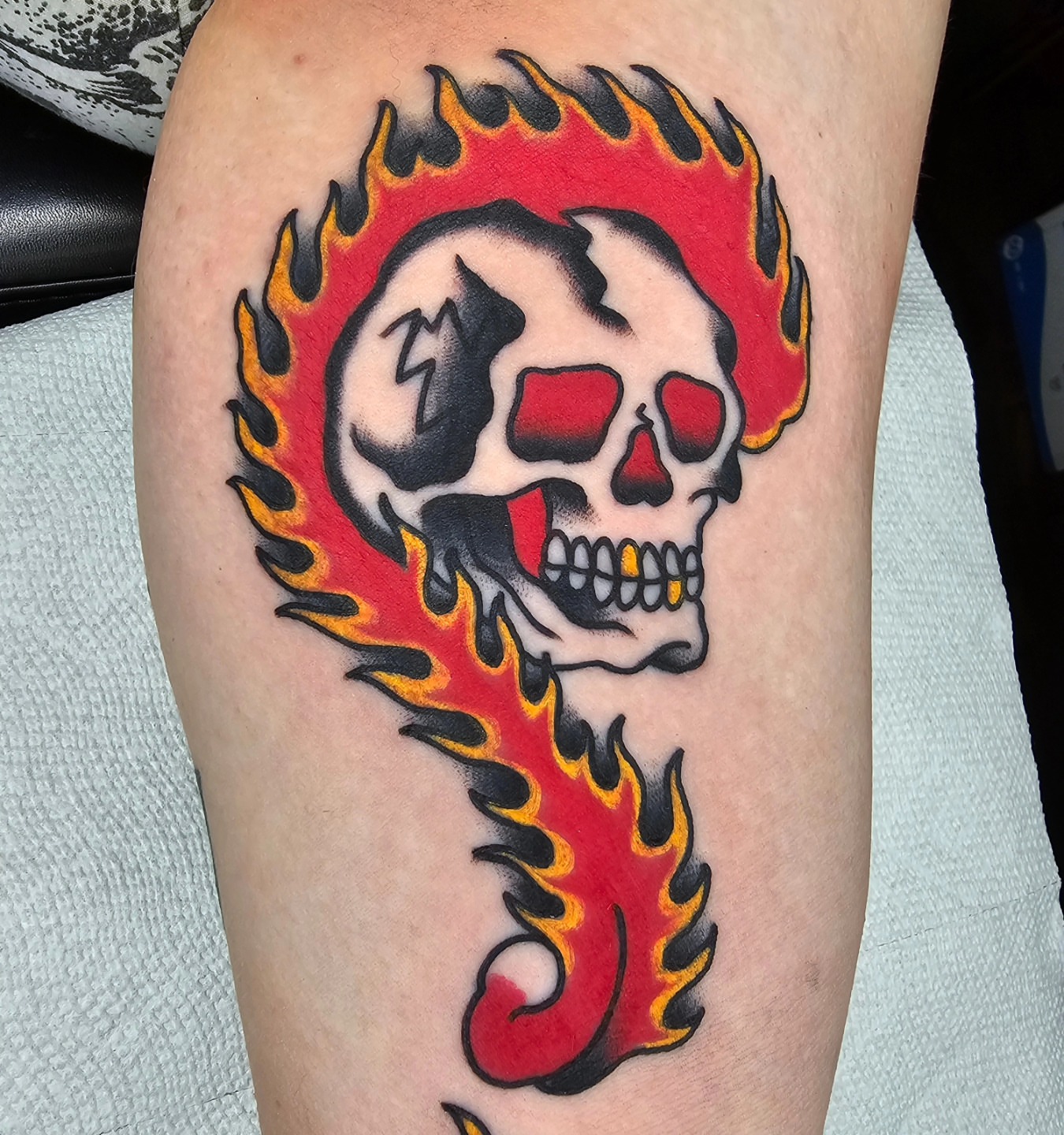 Flaming skull American traditional tattoo on the thigh by Adam Garnek