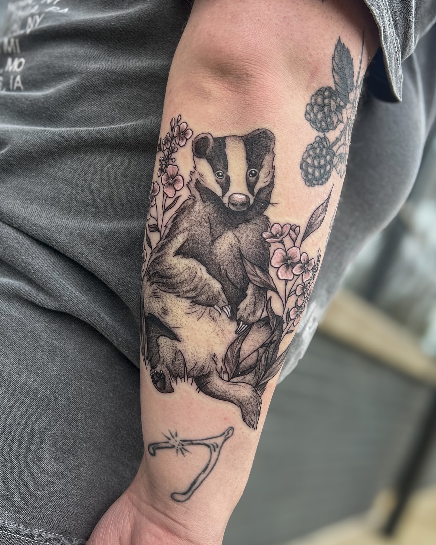 Badger and floral dotwork tattoo on the forearm by Reagan Sutton