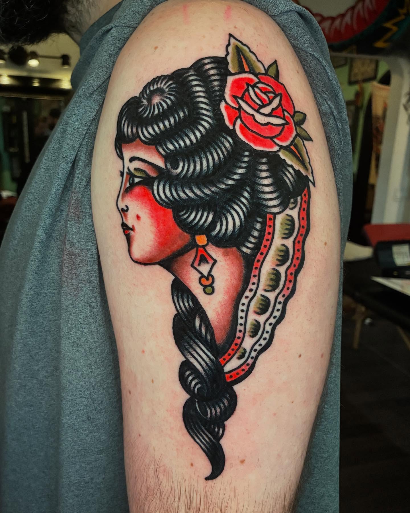 Woman with rose American traditional tattoo on the upper arm by Mike Hudgins