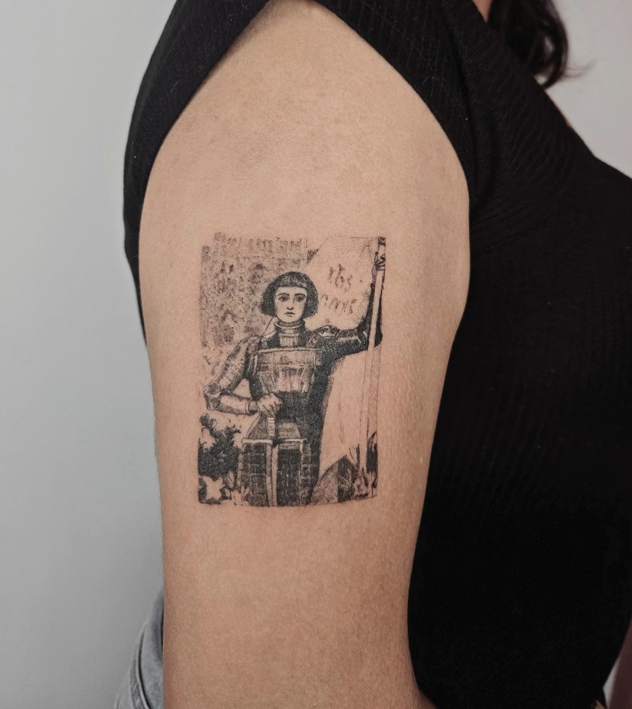 Woman with flag black and grey tattoo on the upper arm by Vintage tattoo