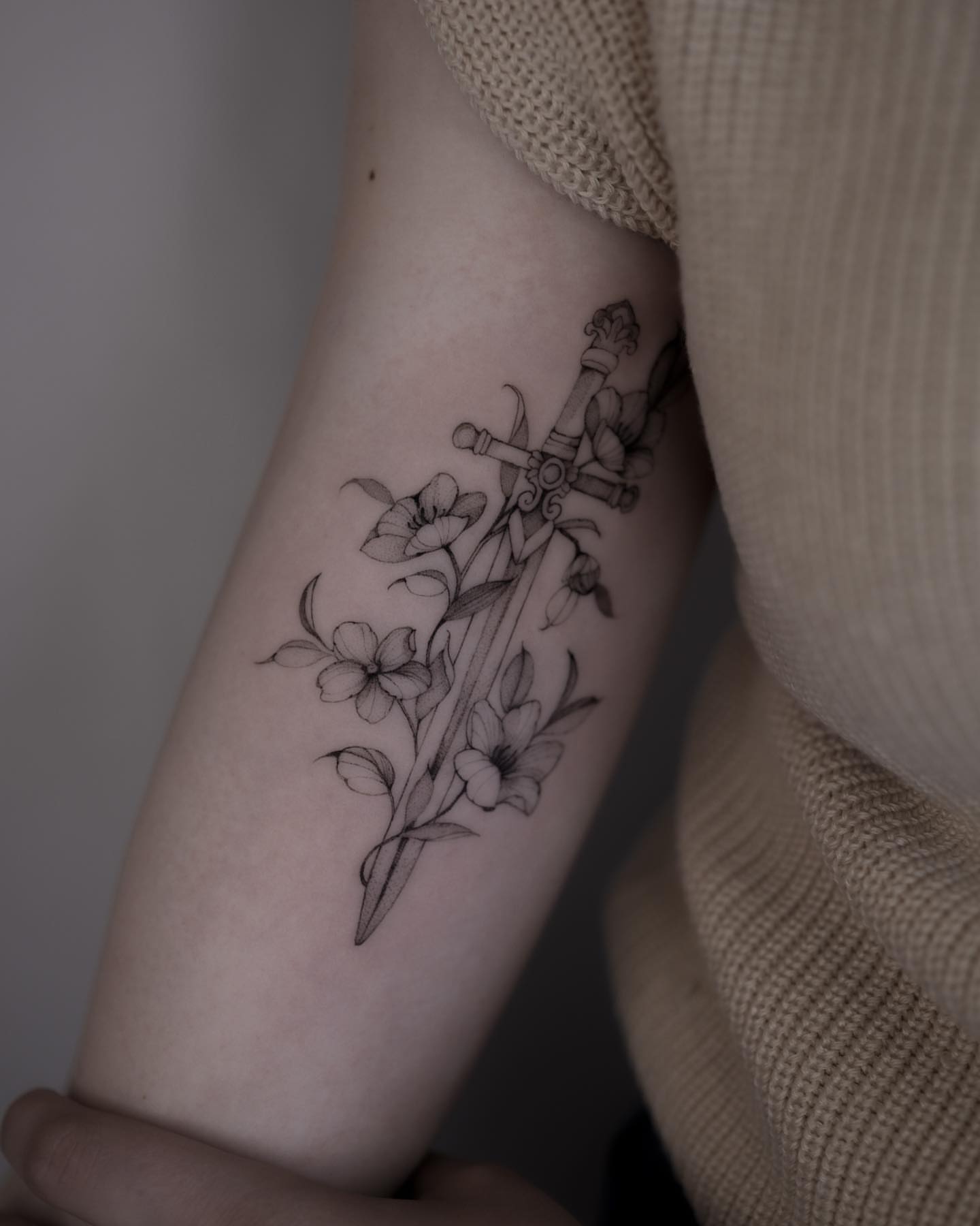 Sword and flowers black and grey tattoo on the forearm by Tattoo artist in Boston