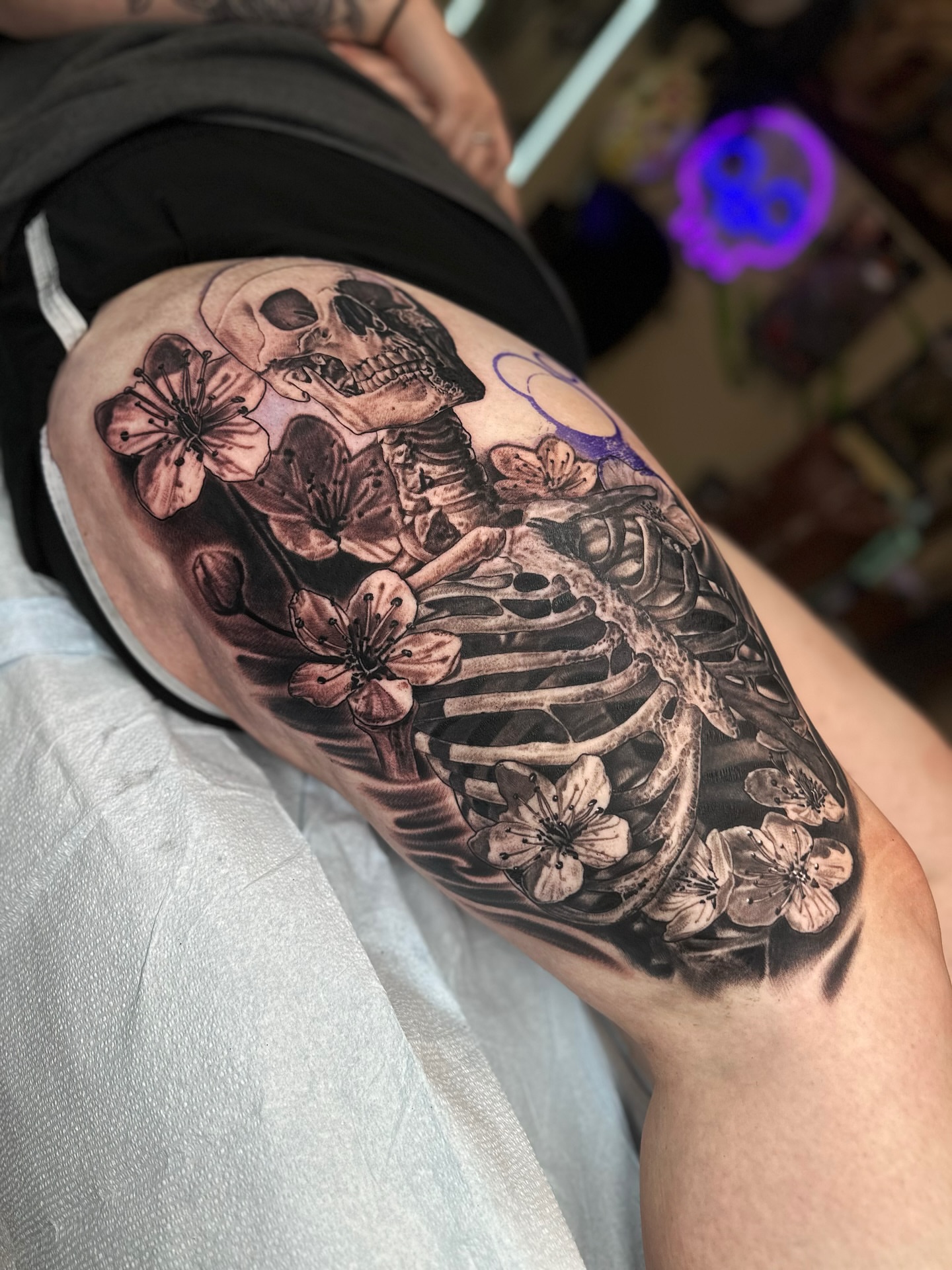 Skeleton with cherry blossoms realism tattoo on the thigh by Jesse White, Mentor, Ohio
