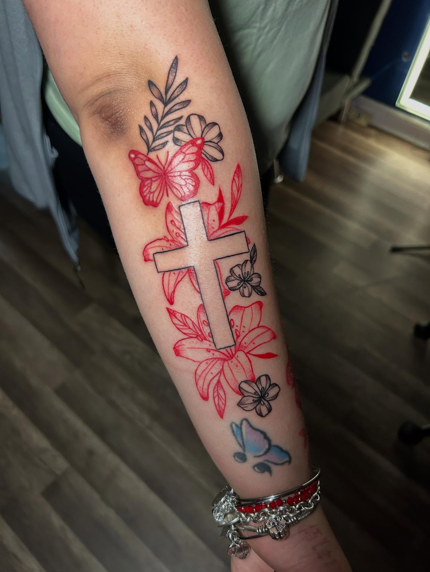 Cross with floral elements new school tattoo on the forearm by Kells