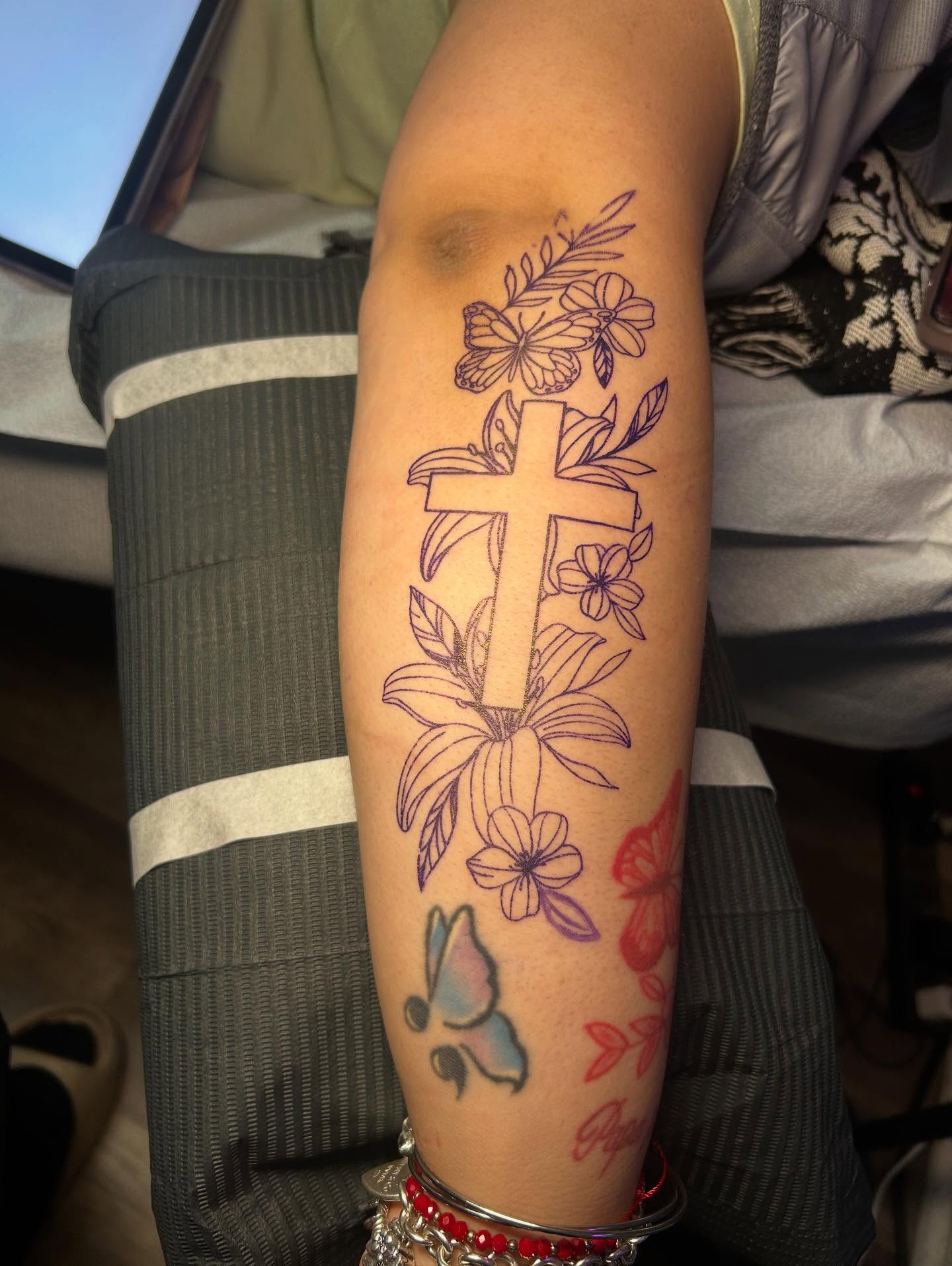 Cross with floral elements neo-traditional tattoo on the forearm by Kells