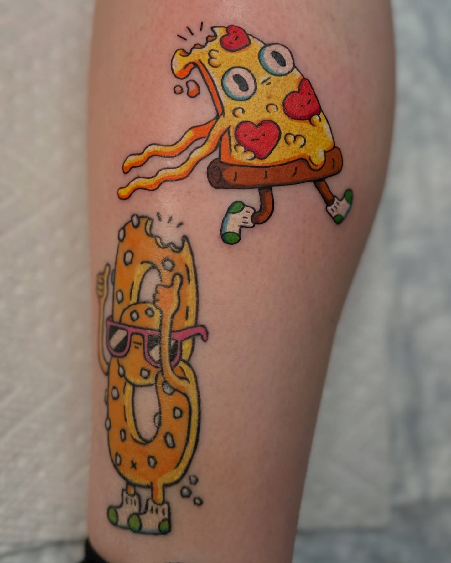 Pizza and donut illustrative tattoo on the thigh by Kellie Burch