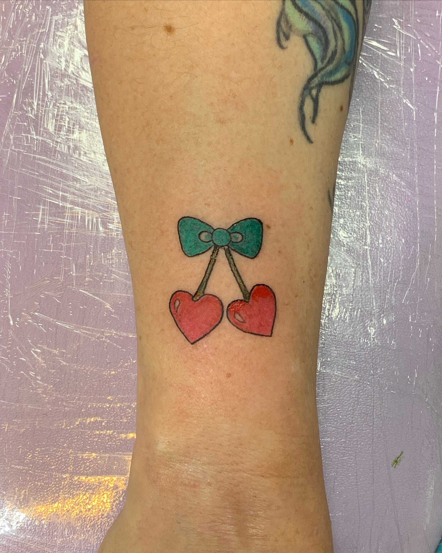 Cherry pair with bow new school tattoo on the forearm by Laura