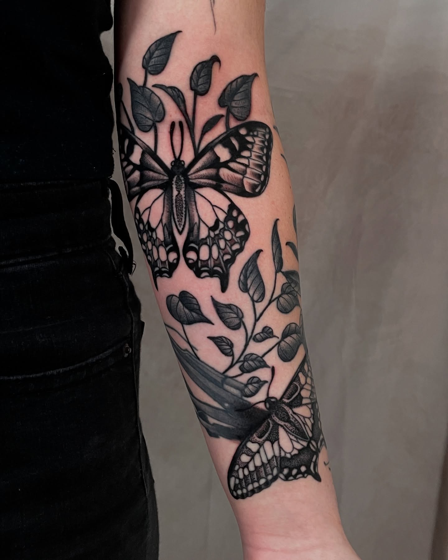Butterfly and leaves black and grey tattoo on the forearm by Austin Clark