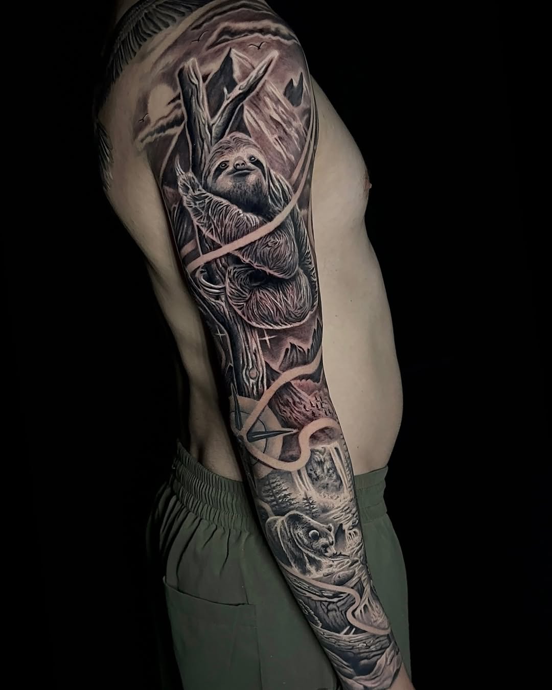 Sloth and bear in nature scene realism tattoo on the upper arm by Clayderman
