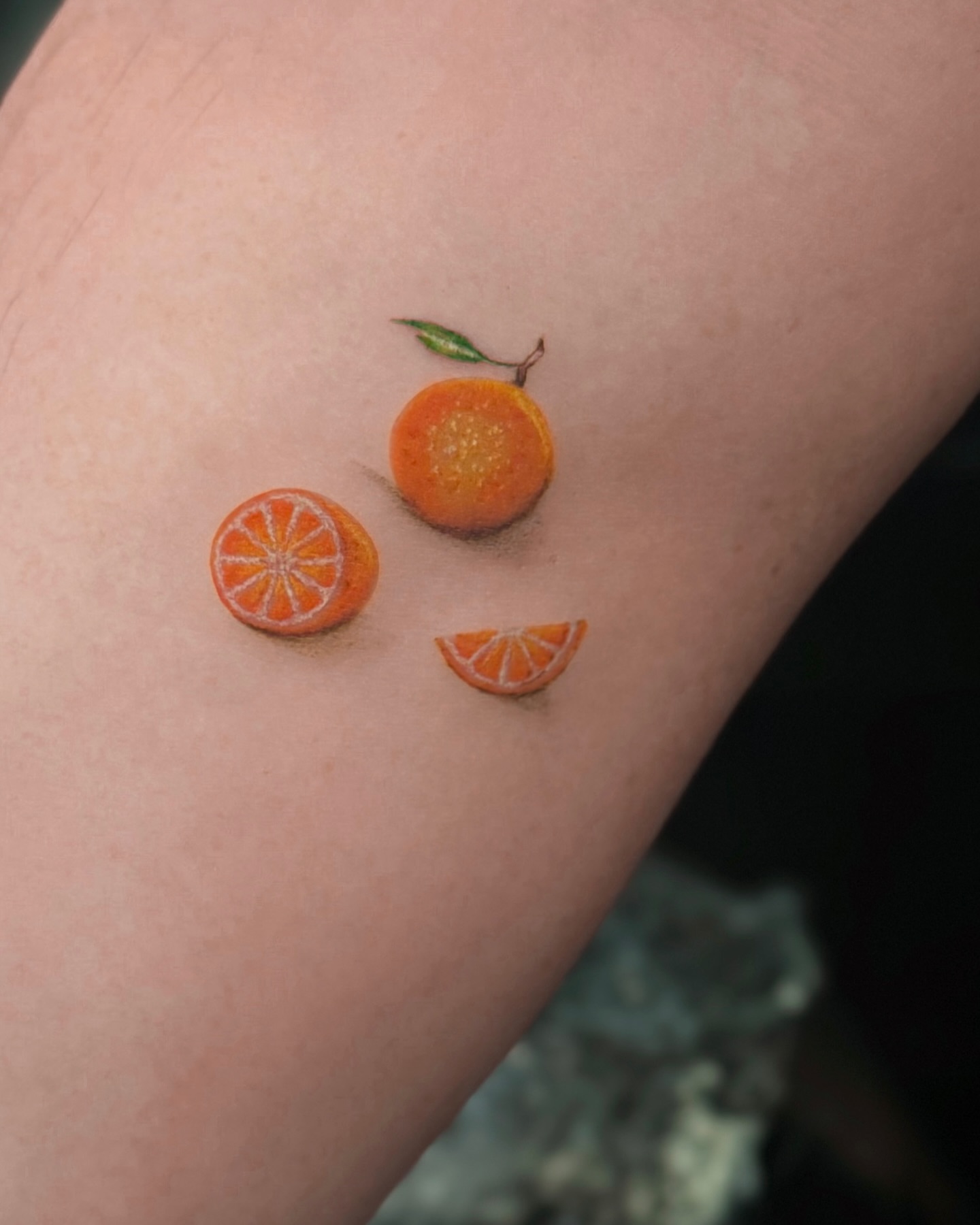 Orange slices realism tattoo on the forearm by Lily K.