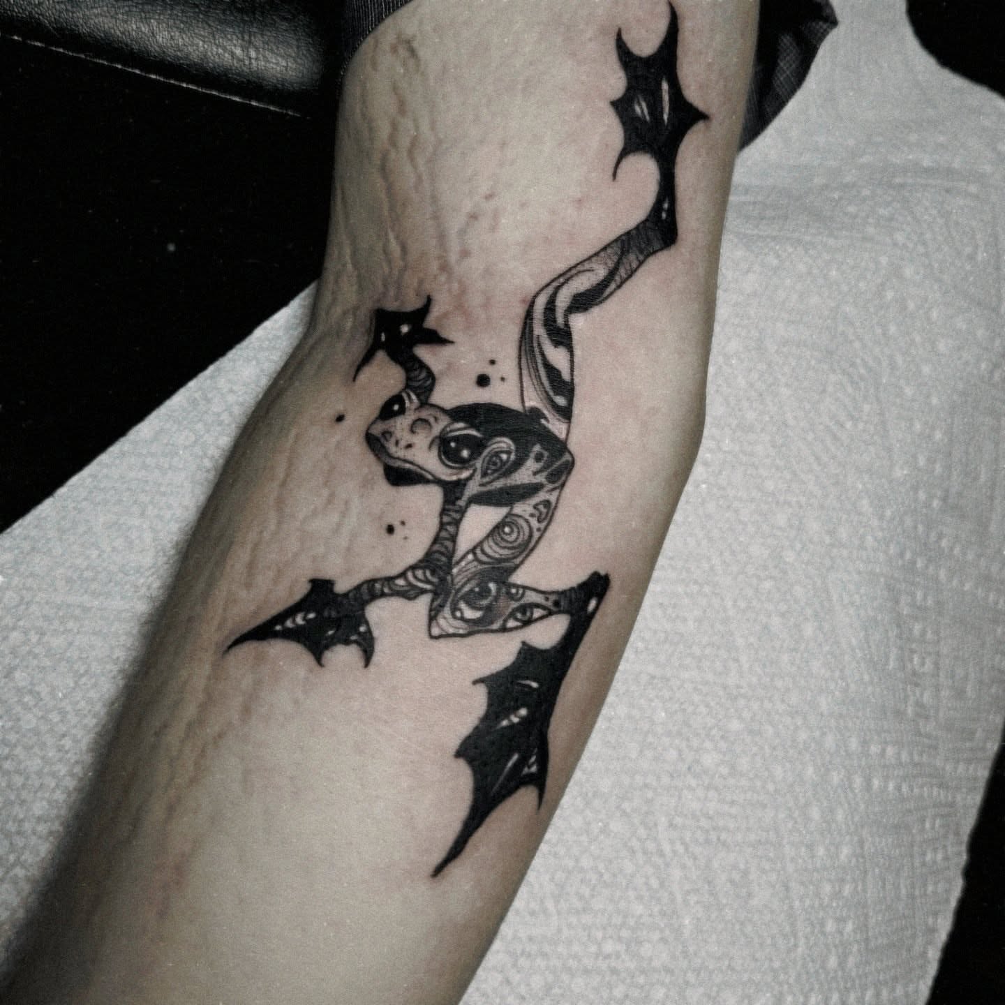 Frog black and grey tattoo on the forearm by Ema Fish