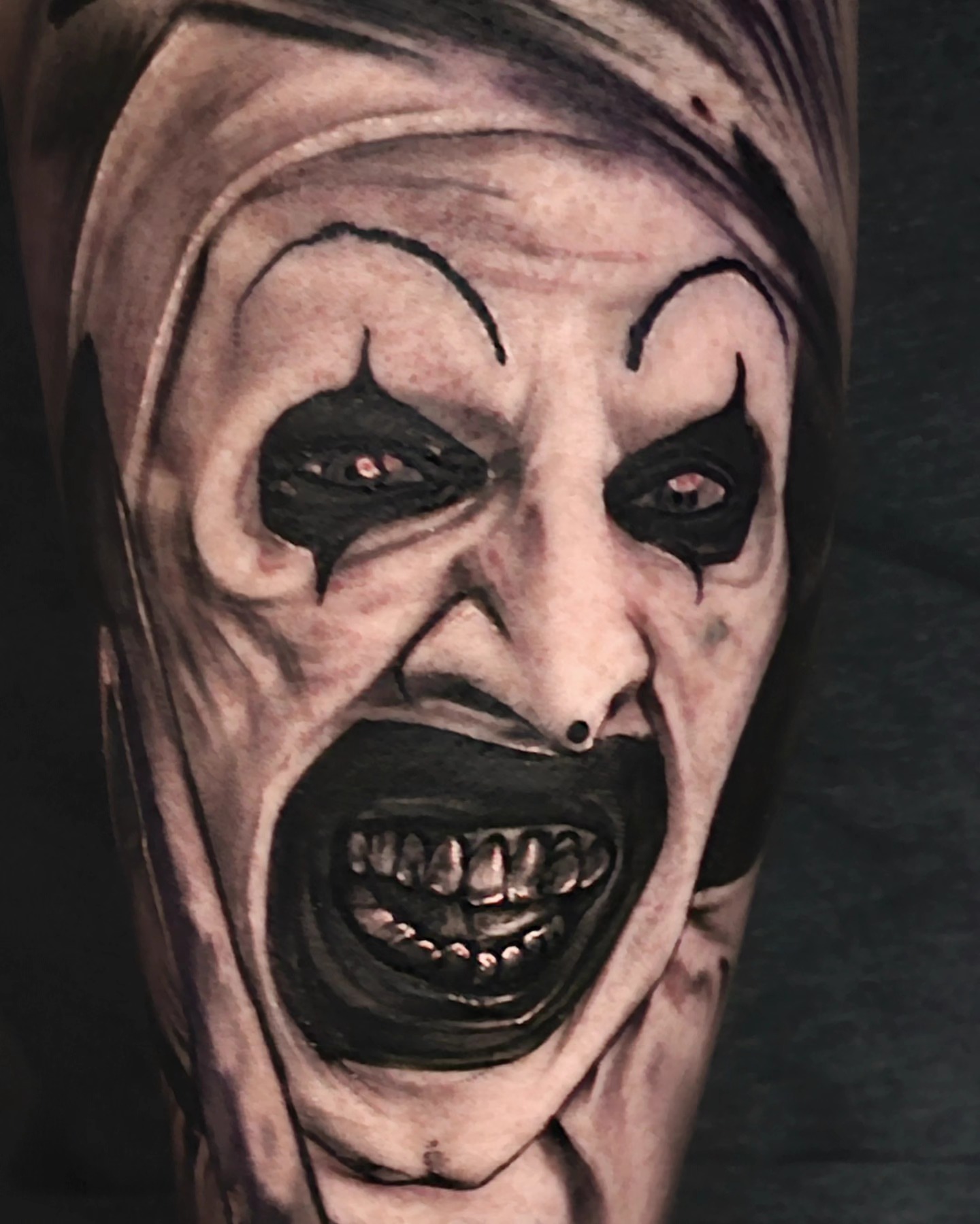 Horror clown dark realism tattoo on the forearm by Christian Mulvey