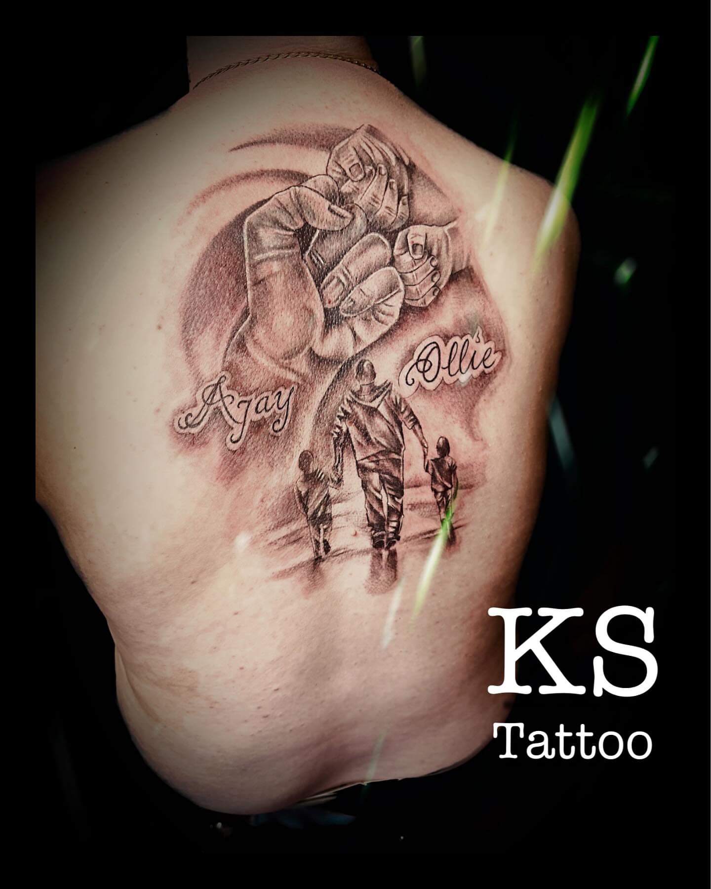 Football player with children black and grey tattoo on the back by Karen Smith