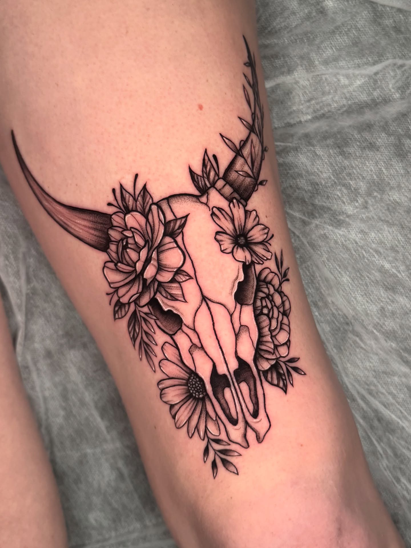 Deer skull with flowers realism tattoo on the forearm by kelsey hackett