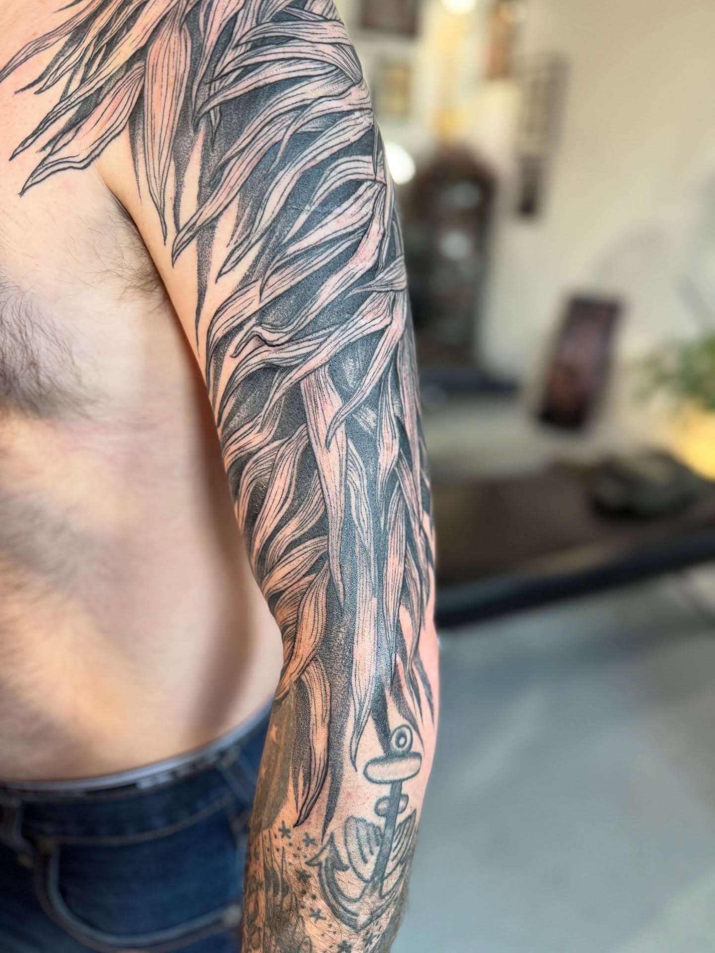 Feather black and grey tattoo on the upper arm by Benjamin Carlson