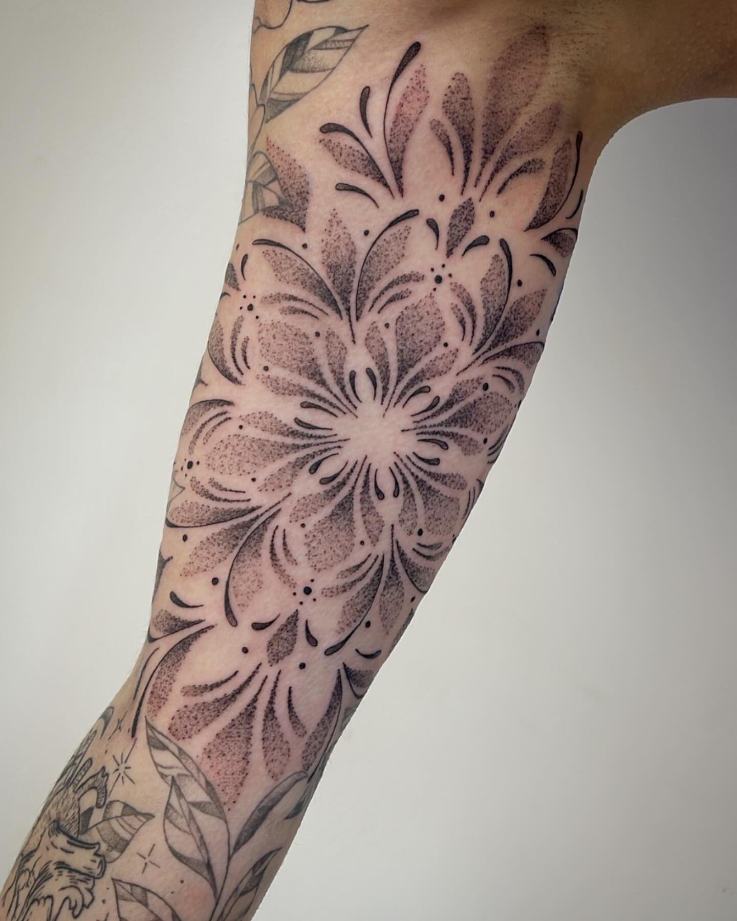 Floral design dotwork tattoo on the forearm by Miesha Busker