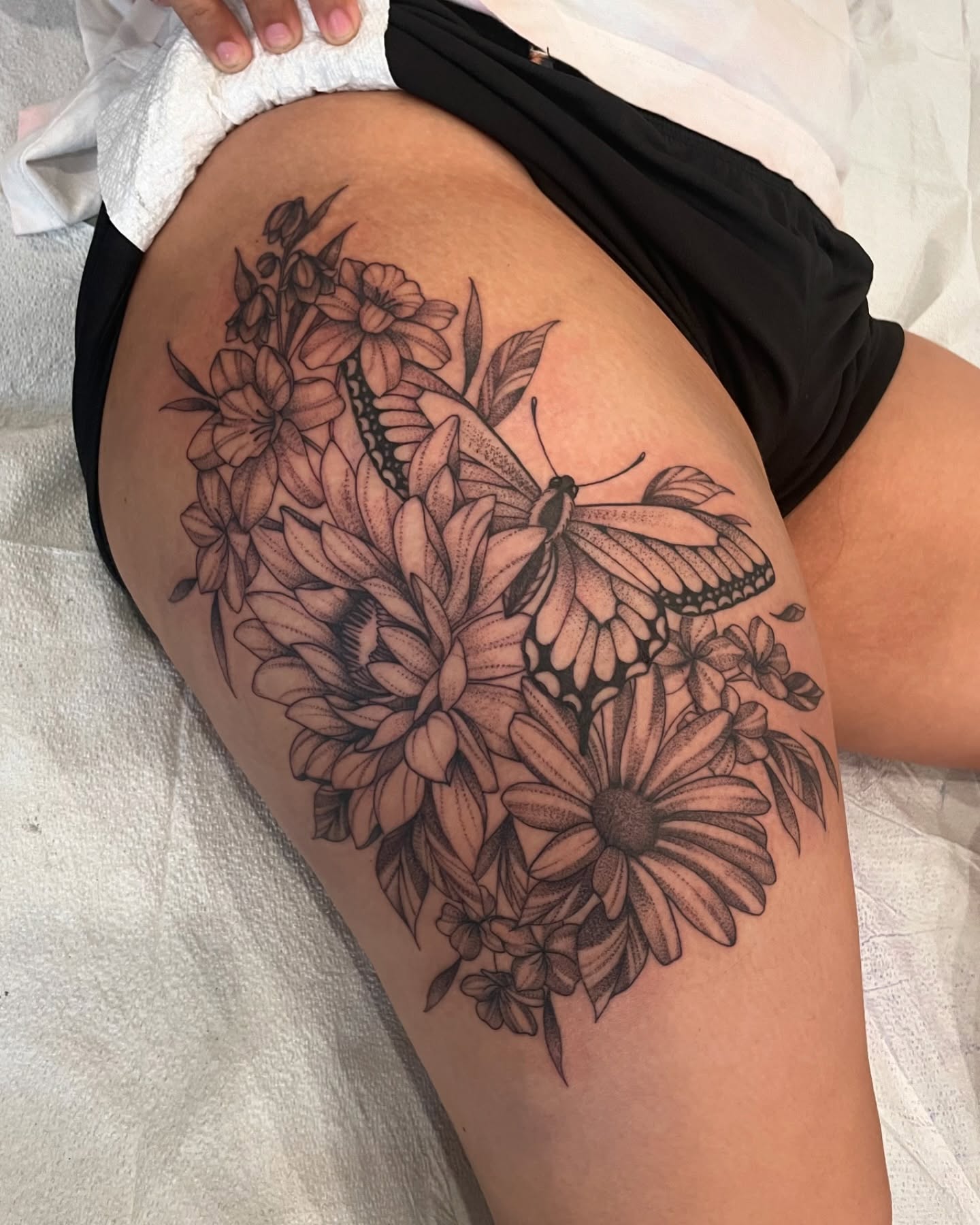 Butterfly and flowers realism tattoo on the thigh by 𝕯𝖔𝖒