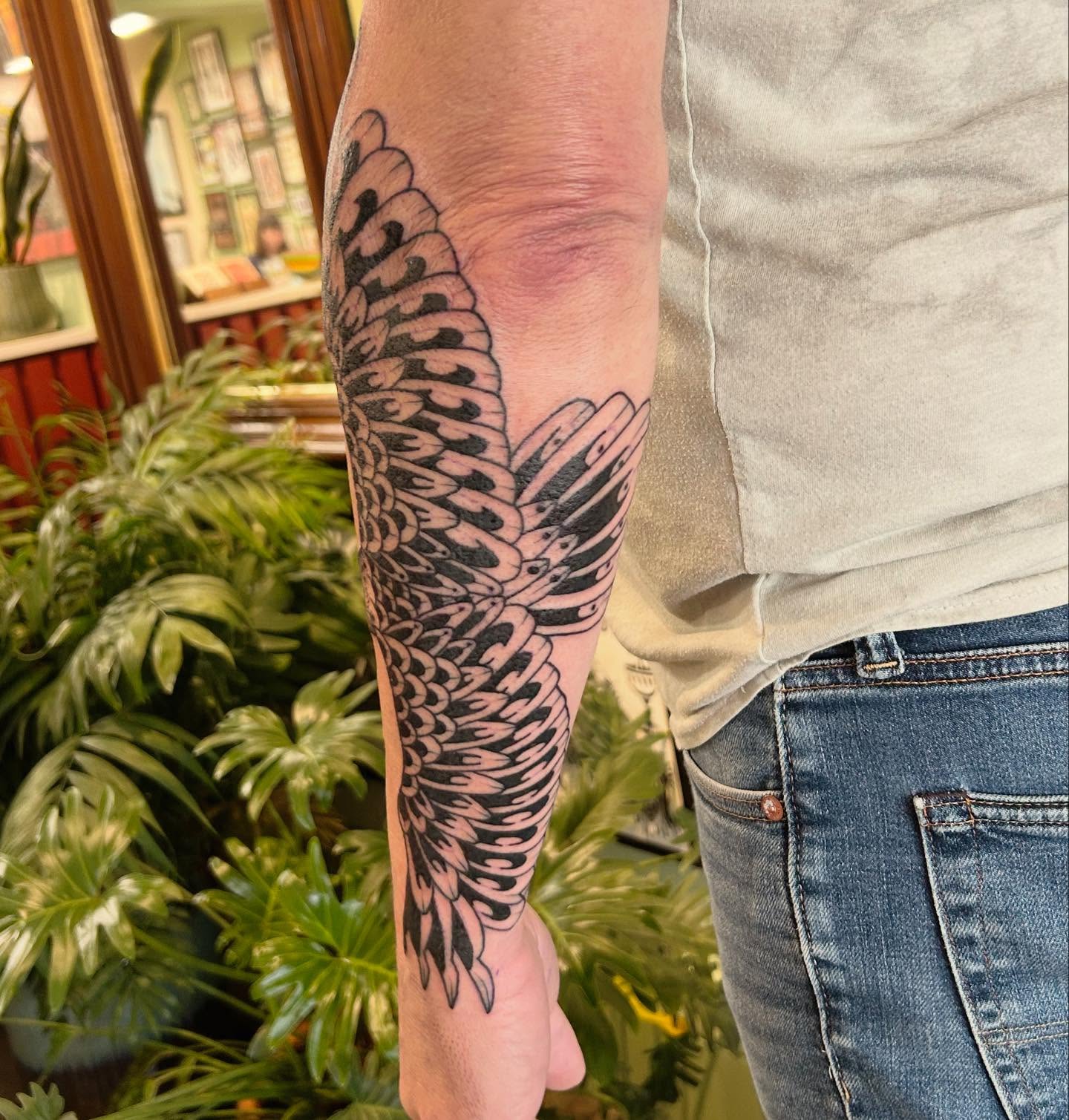 Wing black and grey tattoo on the forearm by Erica Finley