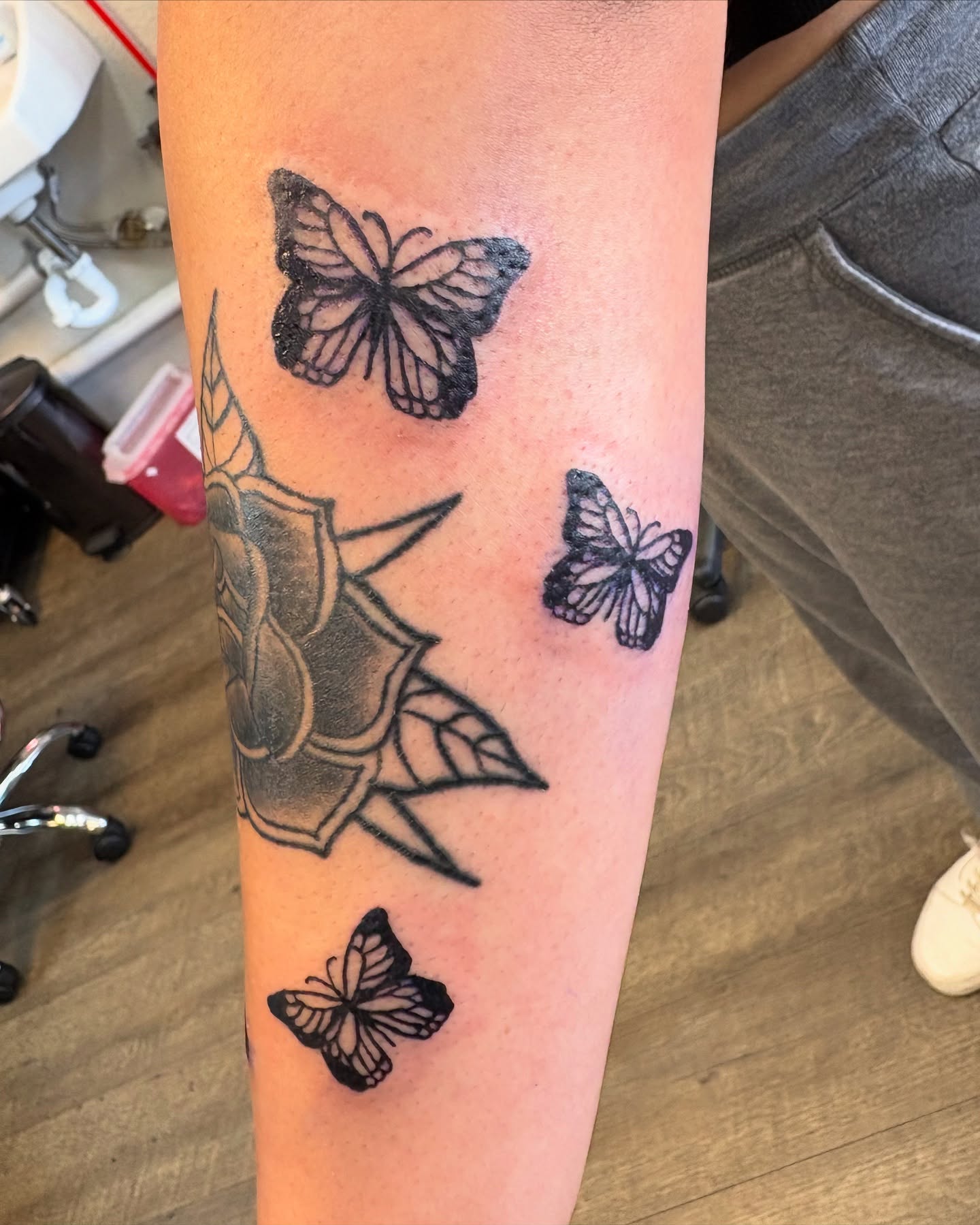 Butterflies and shield black and grey tattoo on the forearm by Tori Anderson, Minneapolis, Minnesota