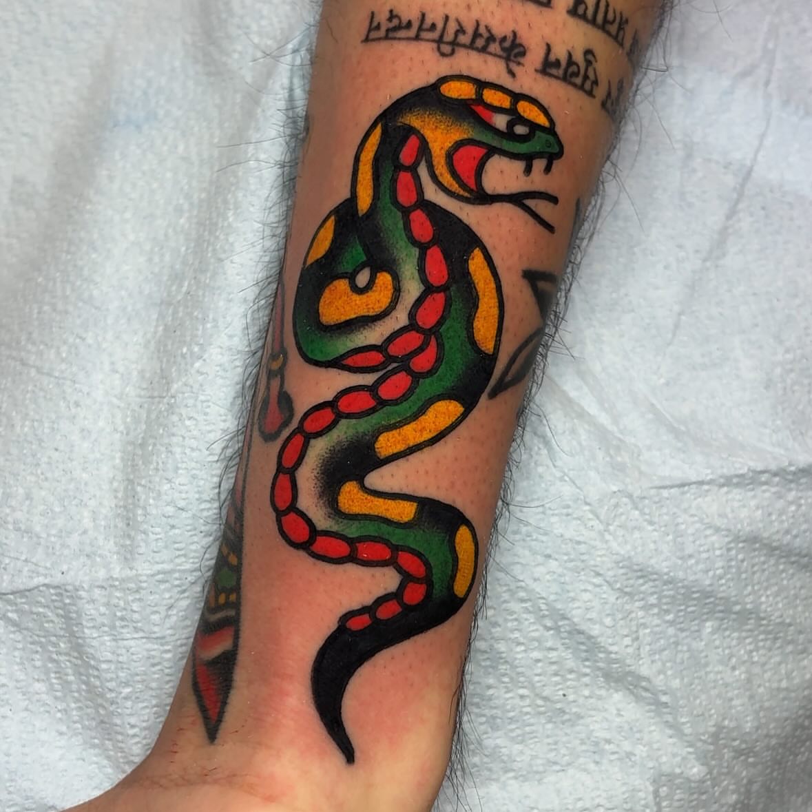 Snake American traditional tattoo on the forearm by John Lemon