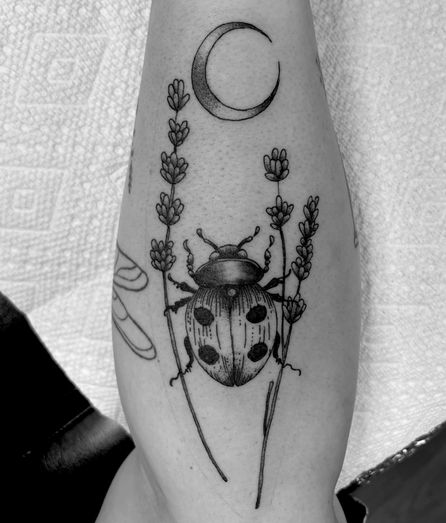 Ladybug and lavender realism tattoo on the forearm by Bryan Black