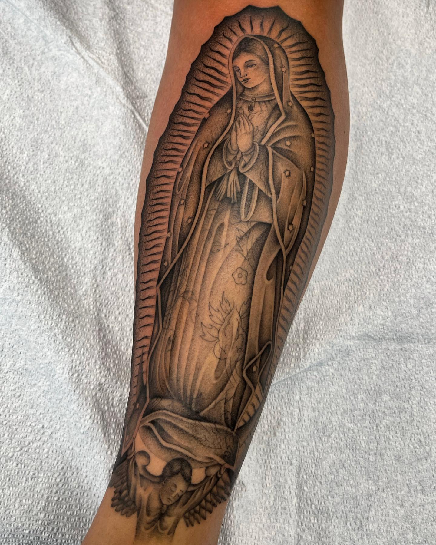 Virgin mary black and grey tattoo on the forearm by Tiyanna Garlic