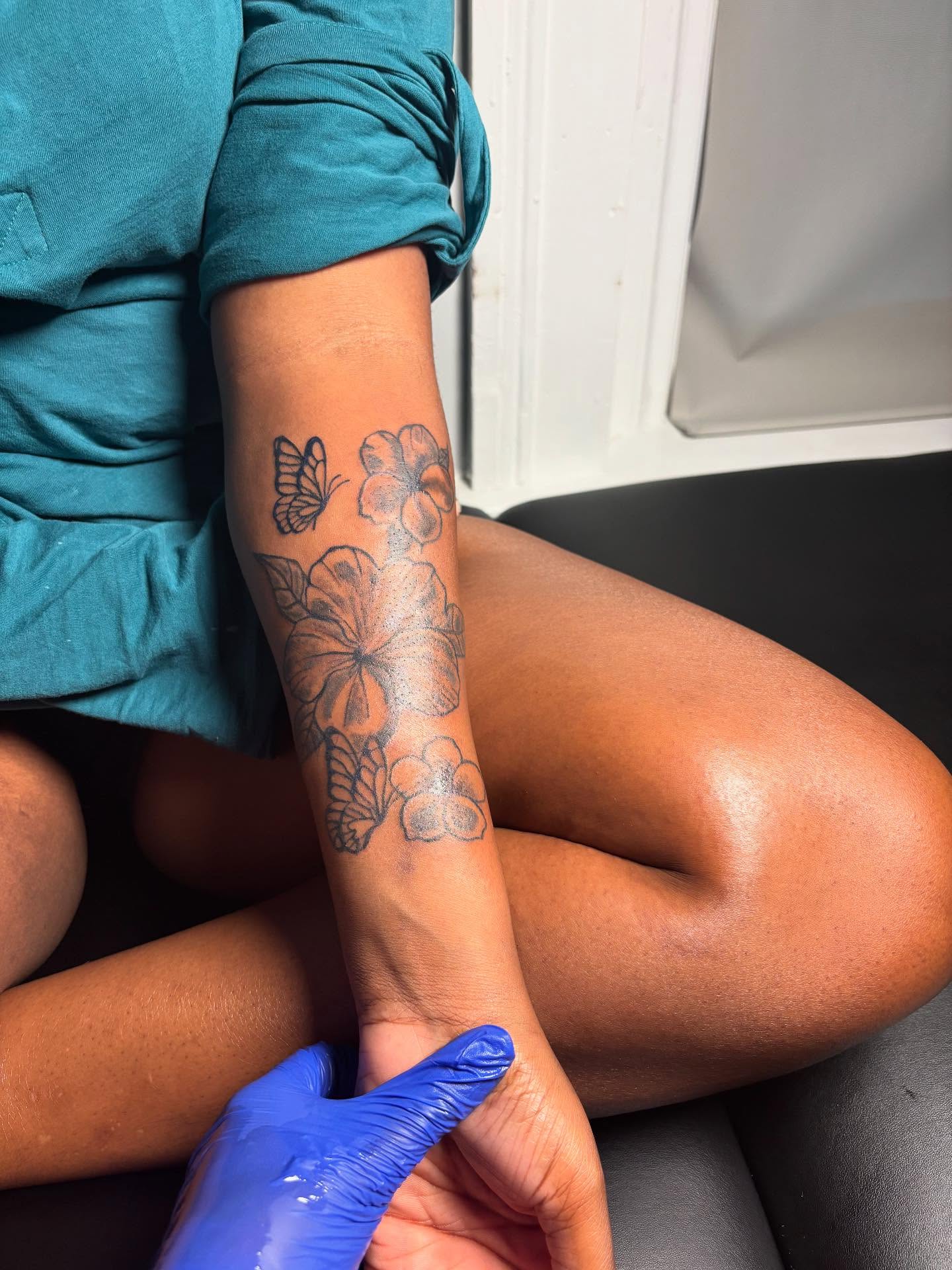 Flowers and butterfly black and grey tattoo on the forearm by Mc X Happo
