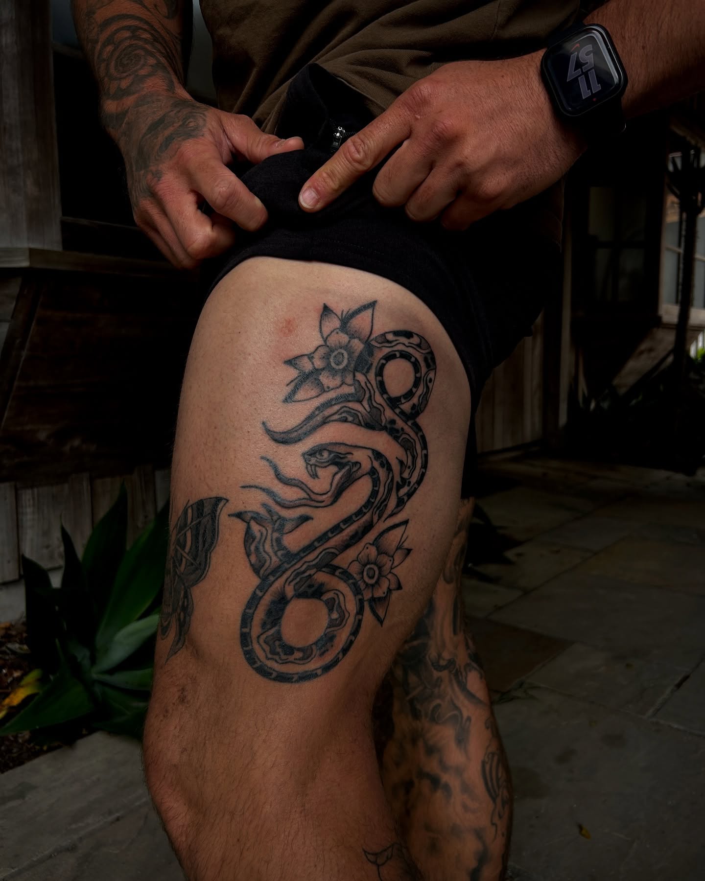 Snake and flowers black and grey tattoo on the thigh by Amara Lyons, Matakana, New Zealand