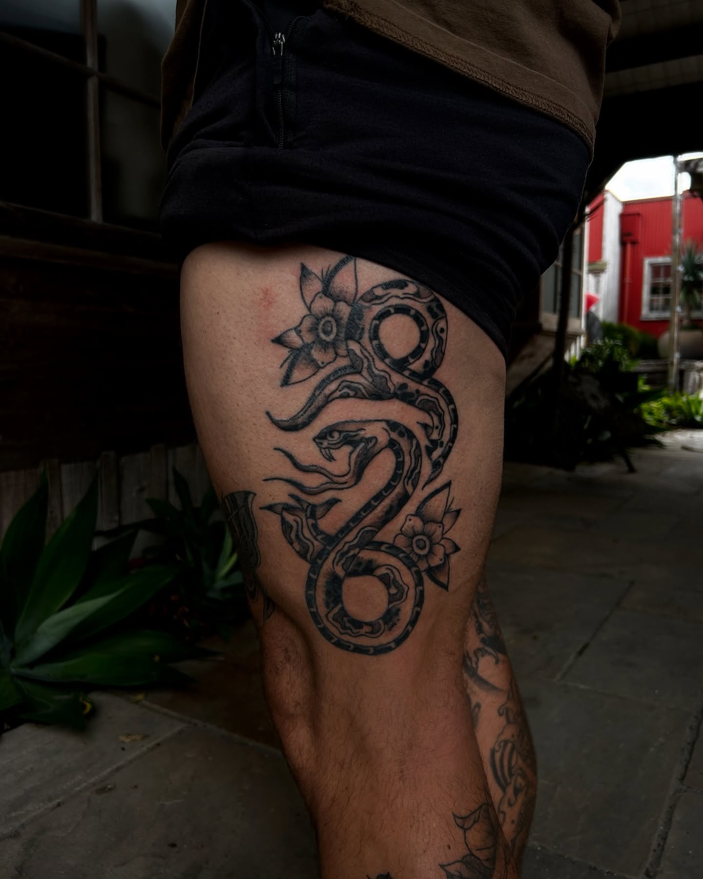 Snake and flowers black and grey tattoo on the thigh by Amara Lyons, Matakana, New Zealand