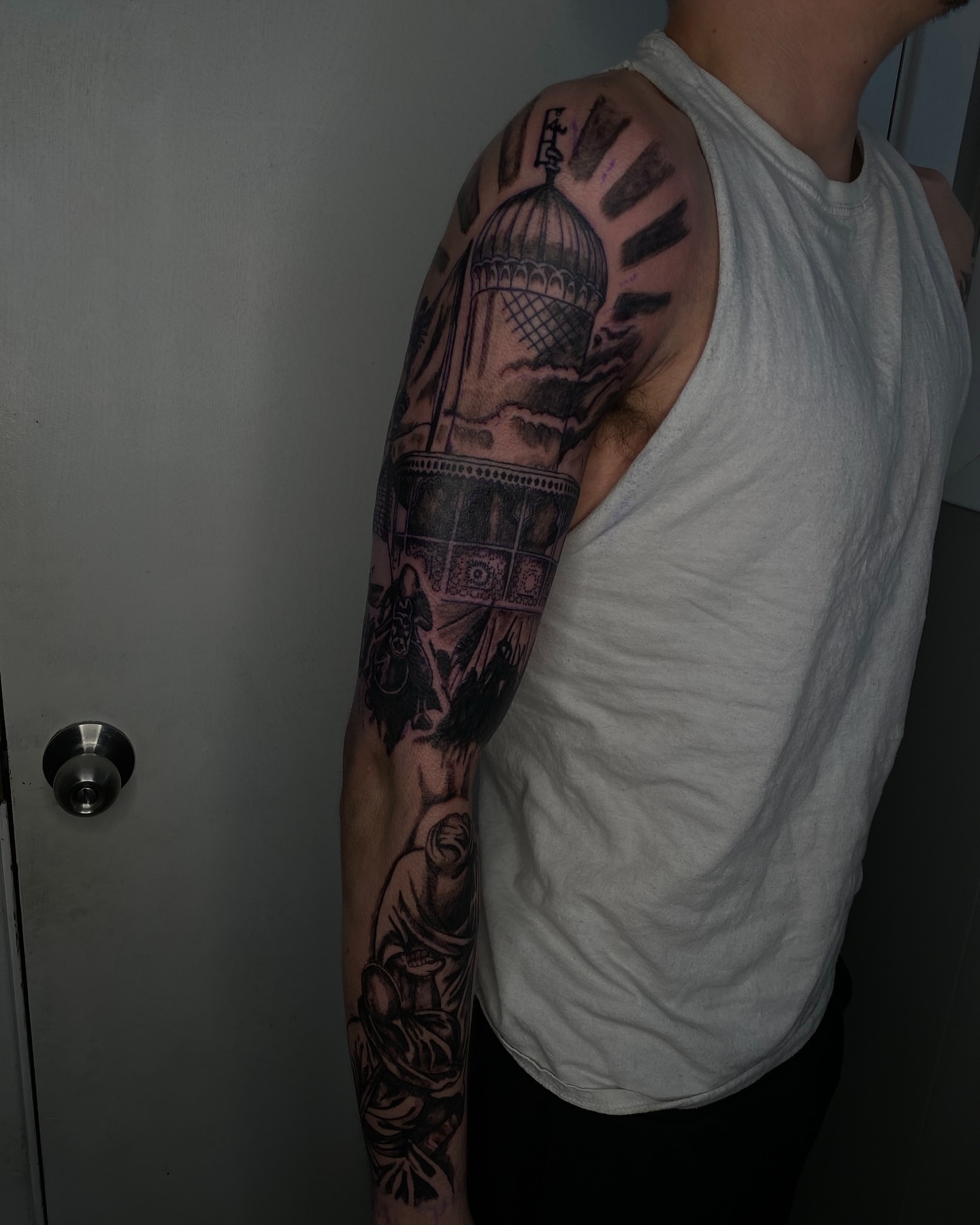 Mosque and figures black and grey tattoo on the upper arm by Evan Chastain