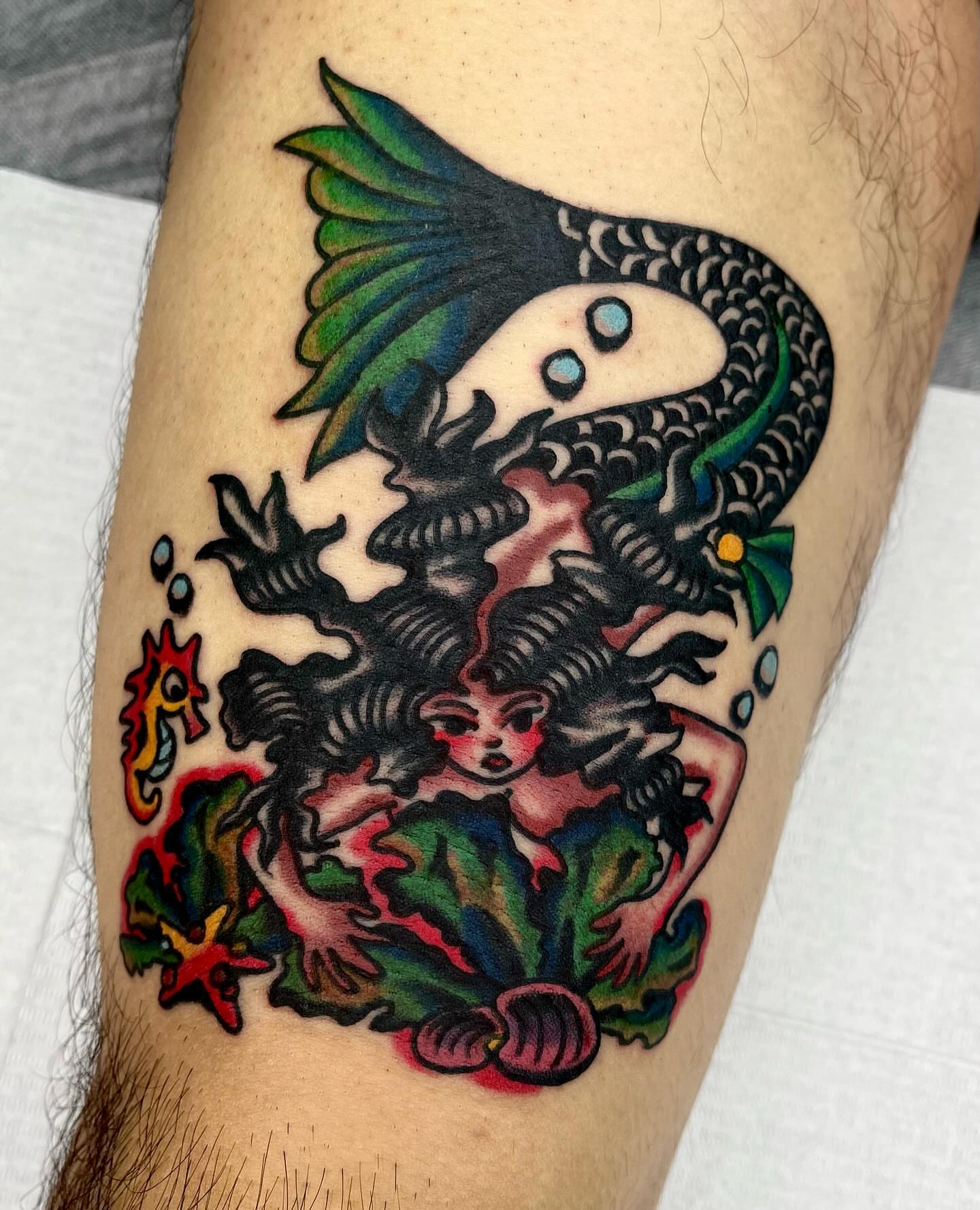 Mermaid and fish American traditional tattoo on the thigh by Jimmy Ho
