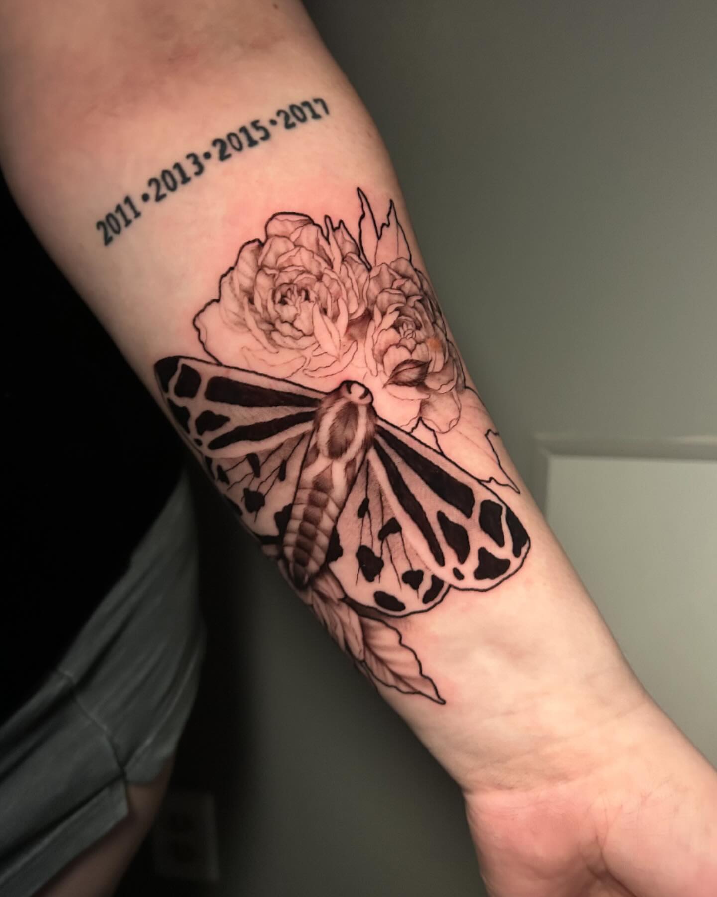Moth and flowers black and grey tattoo on the forearm by Adrian Michigan Tattoo Artist