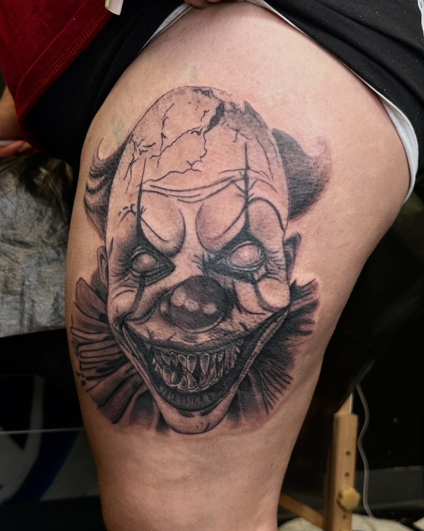 Clown face black and grey tattoo on the thigh by Kimberly landin